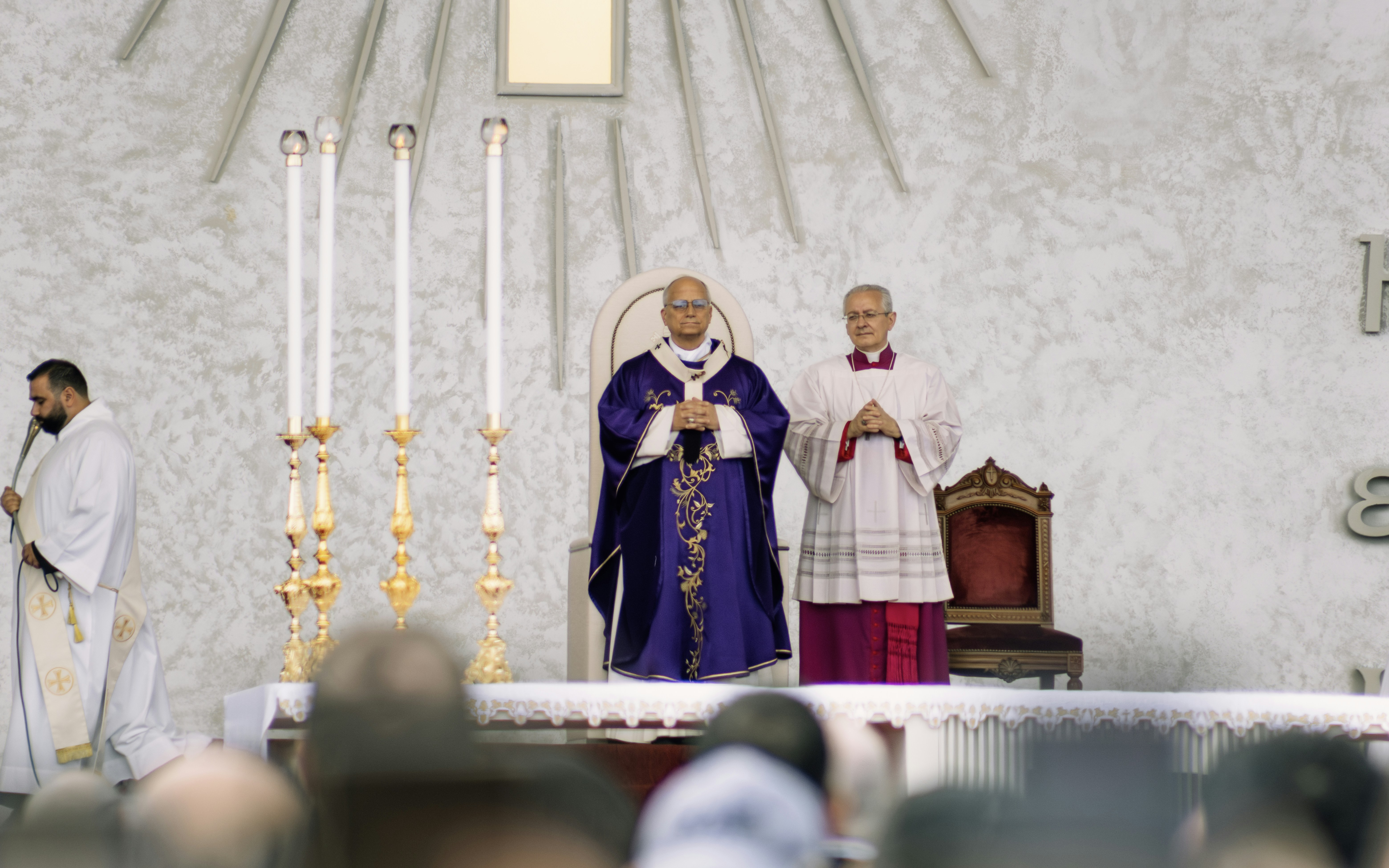 Two clergymen in ceremonial robes stand on stage.