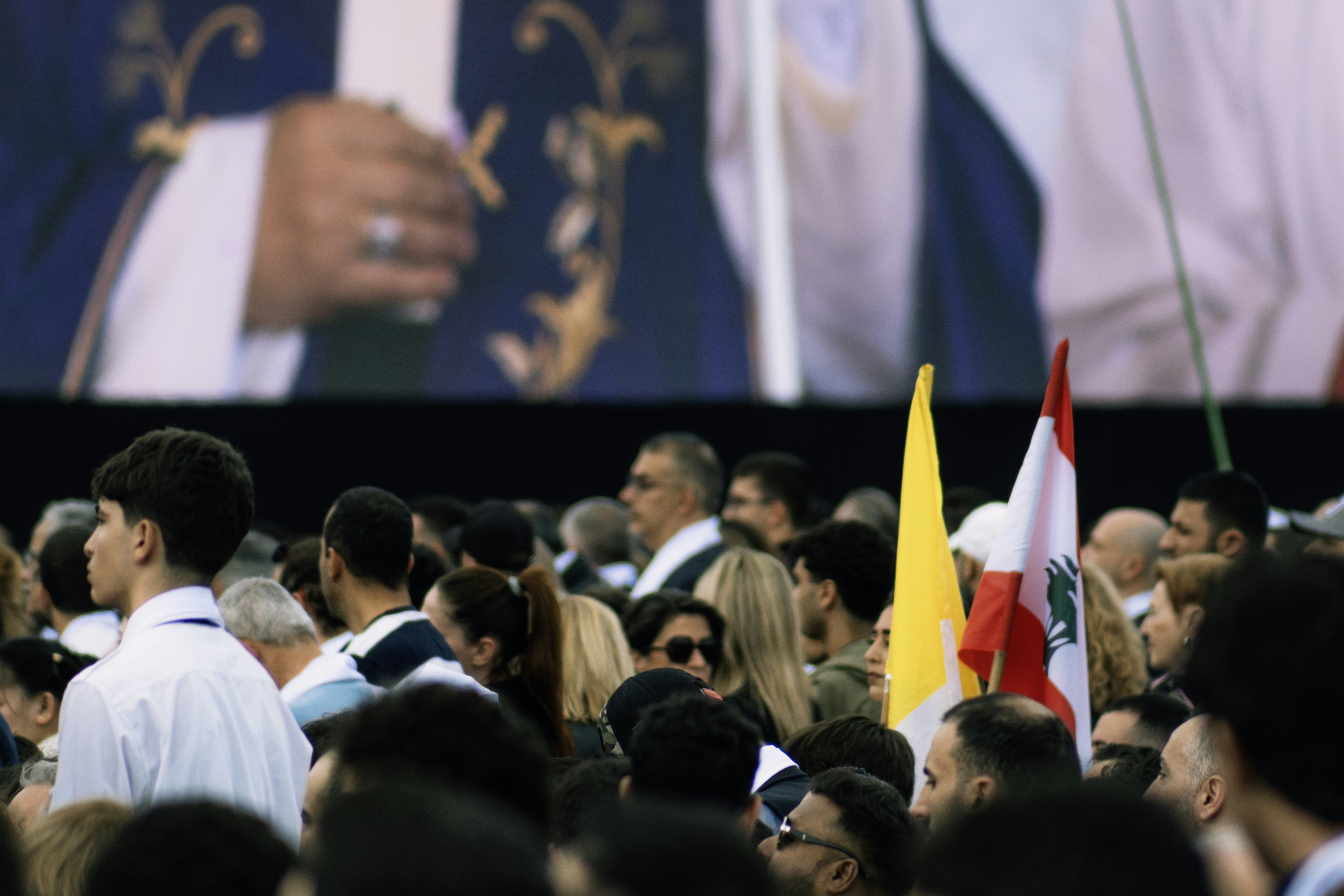 A crowd watches a large screen at an event.