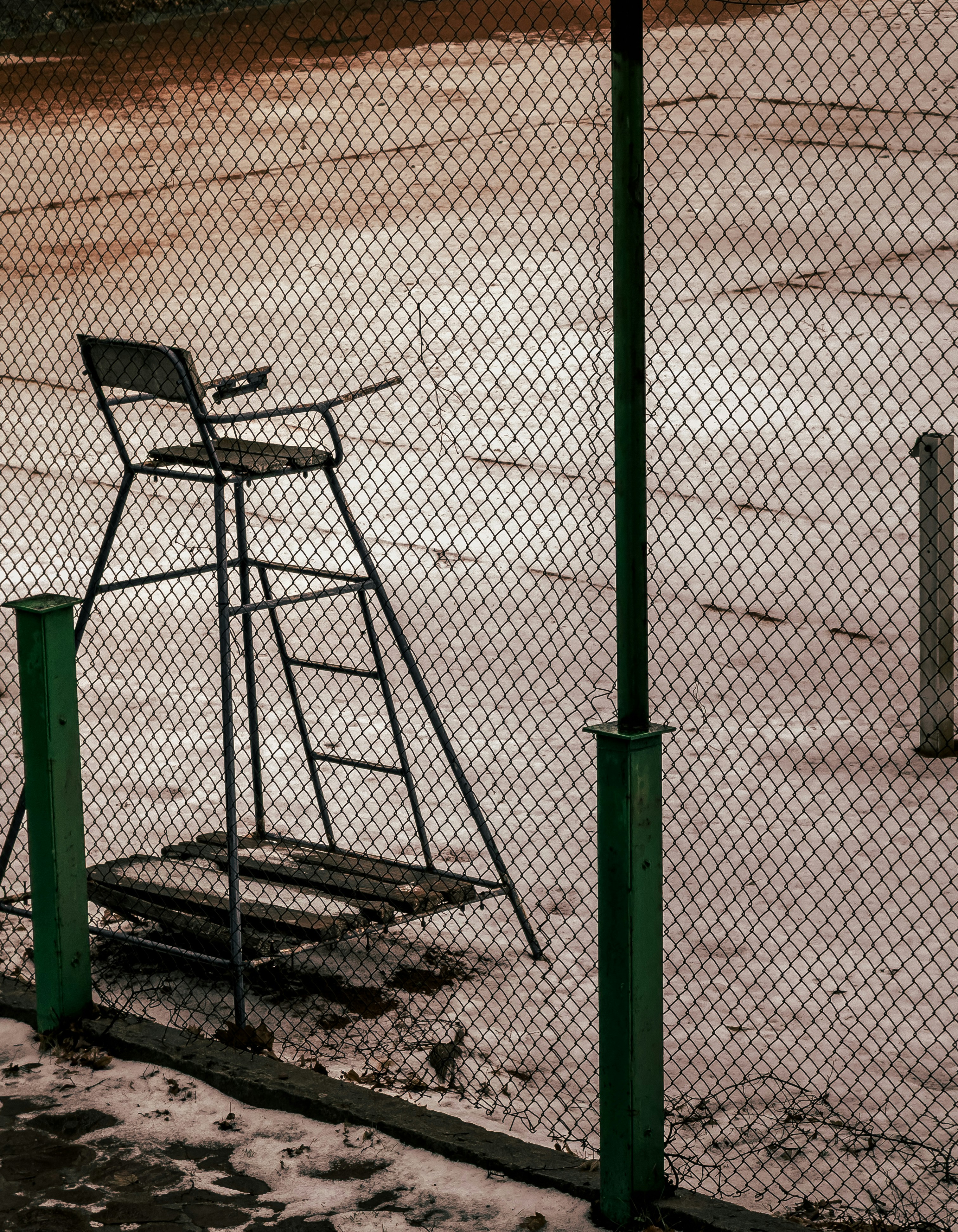 Empty umpire chair behind a chain-link fence