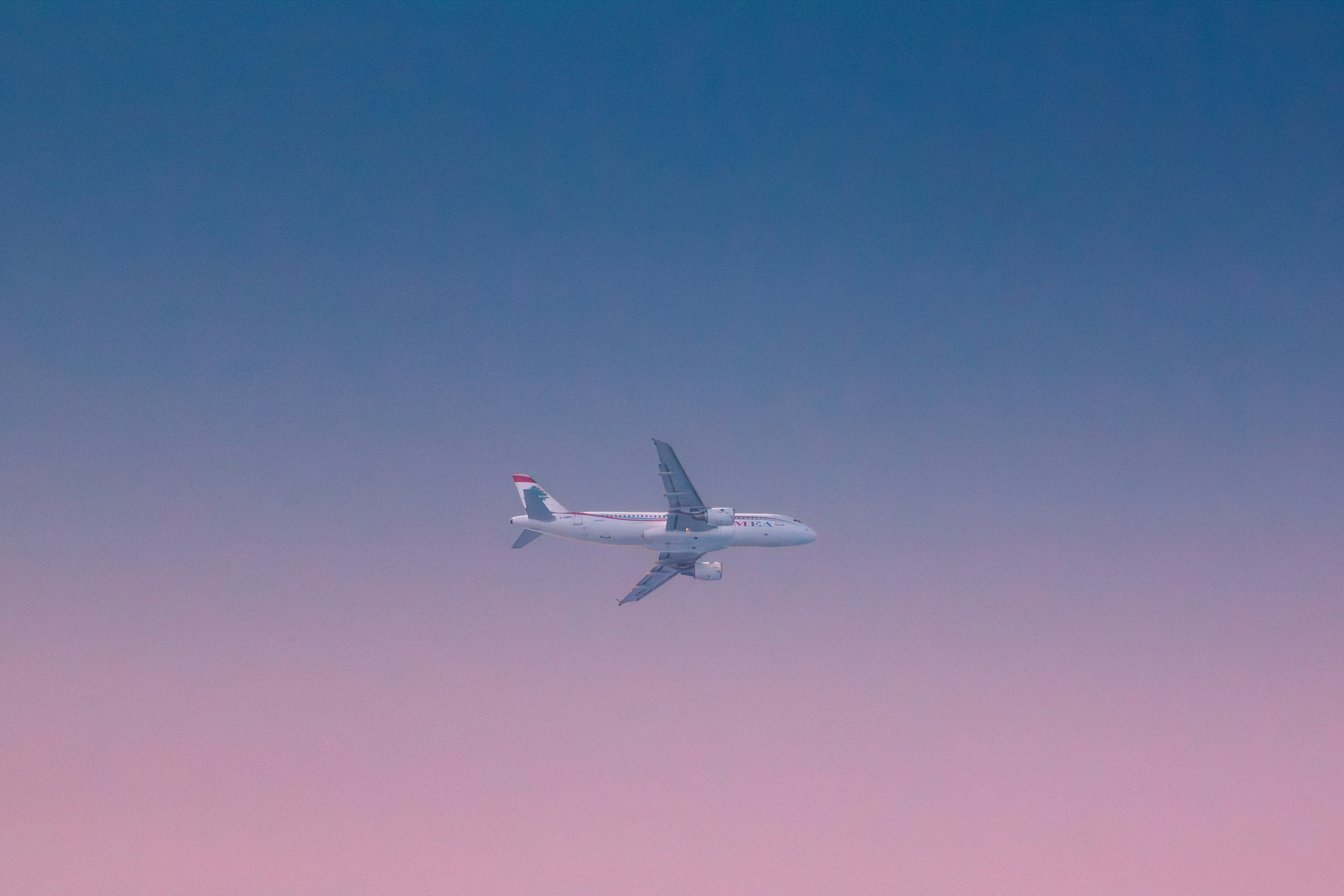 A commercial airplane flying in a gradient sky.