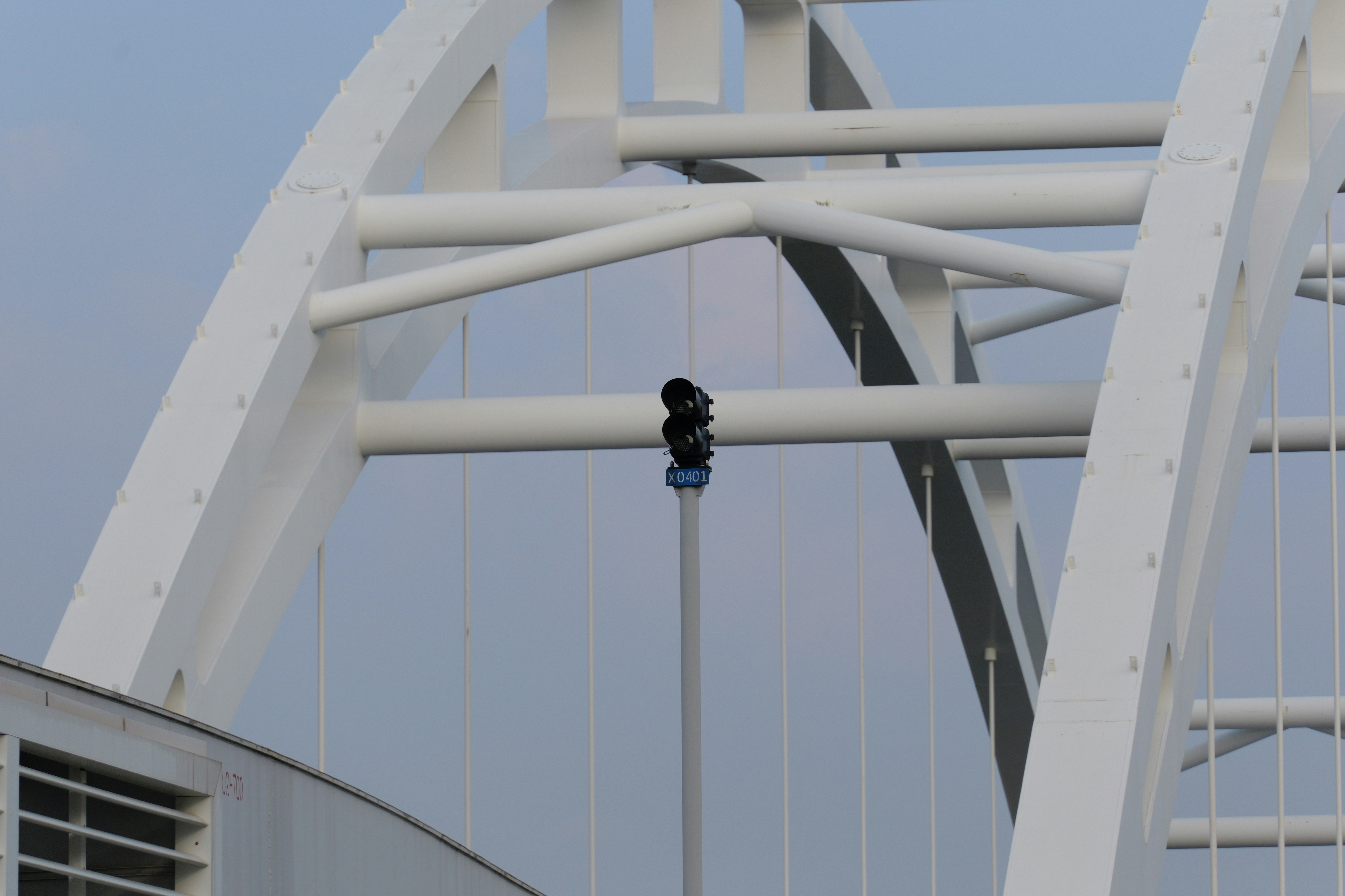White steel bridge structure against a pale sky.