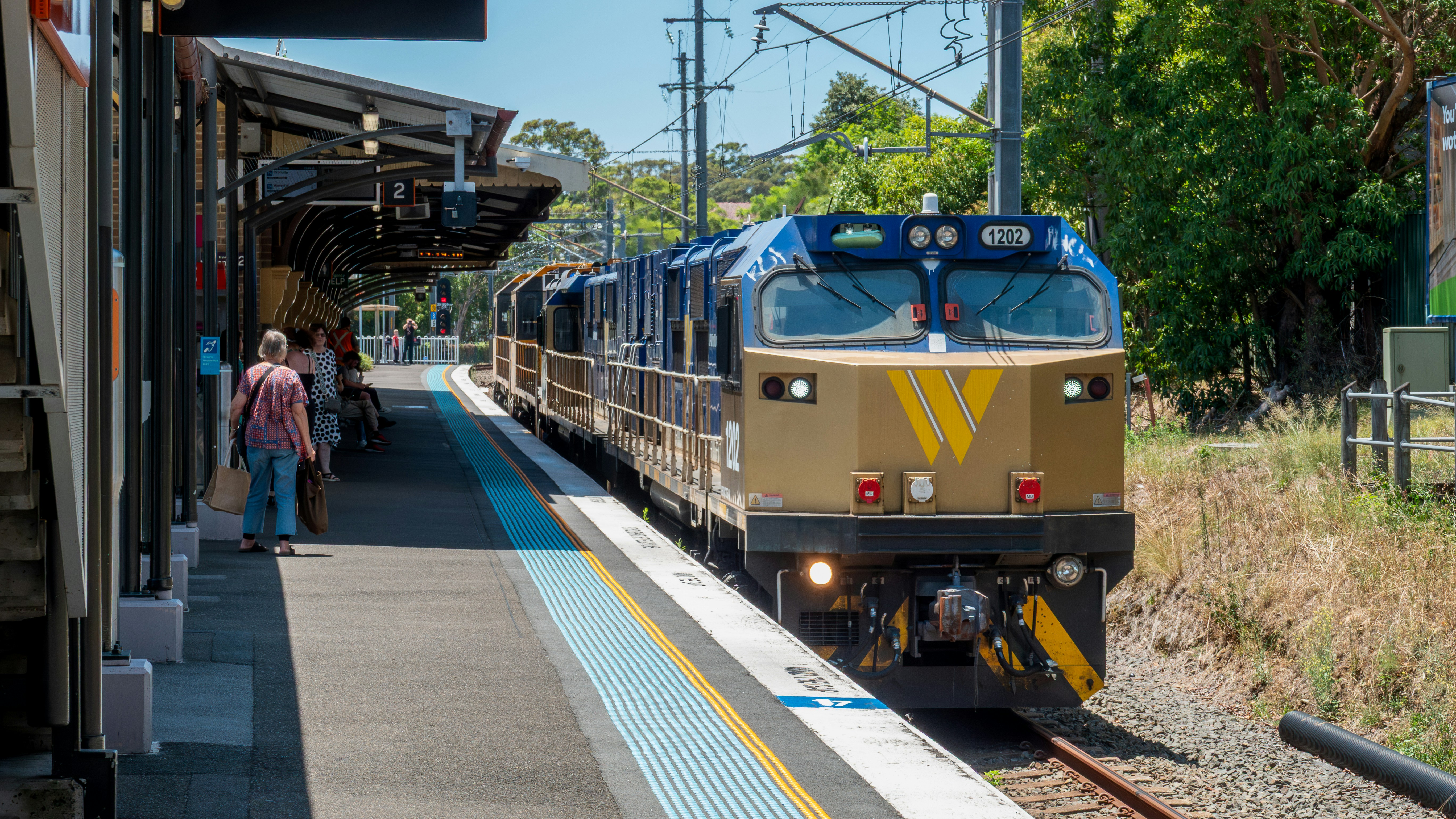 Train arriving at a sunny station platform.