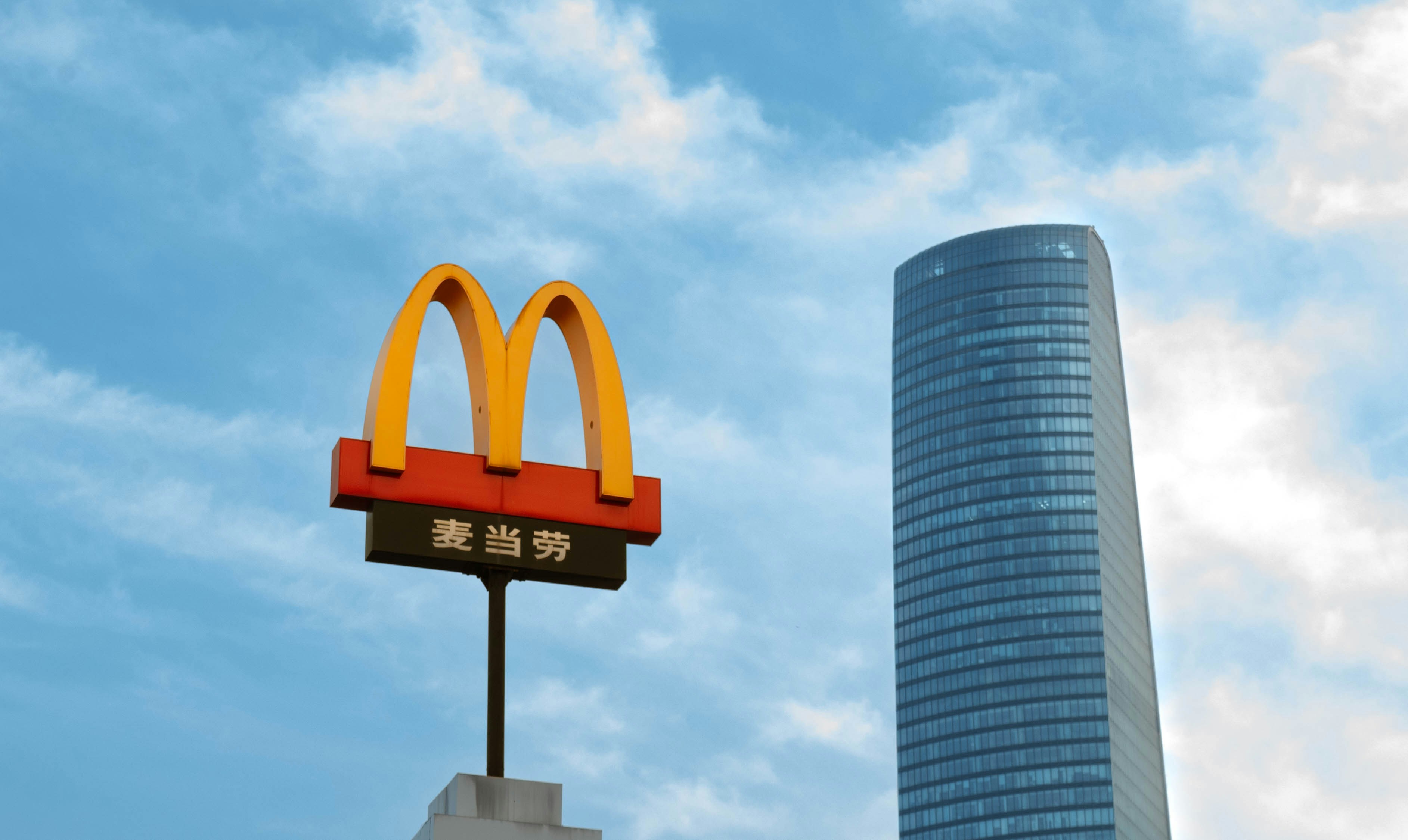 Mcdonald's sign next to a modern skyscraper.