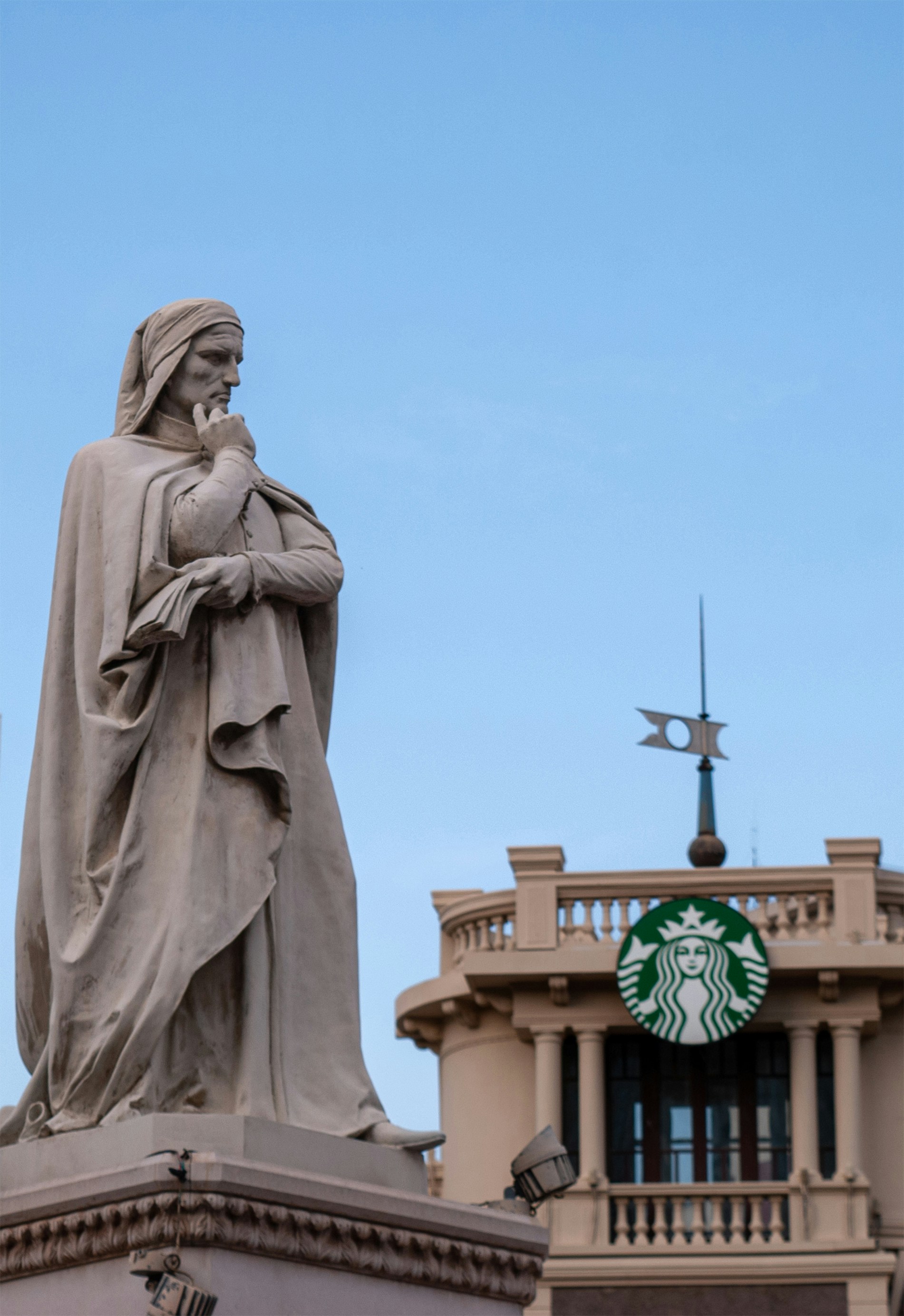 Statue of dante alighieri with starbucks logo behind.