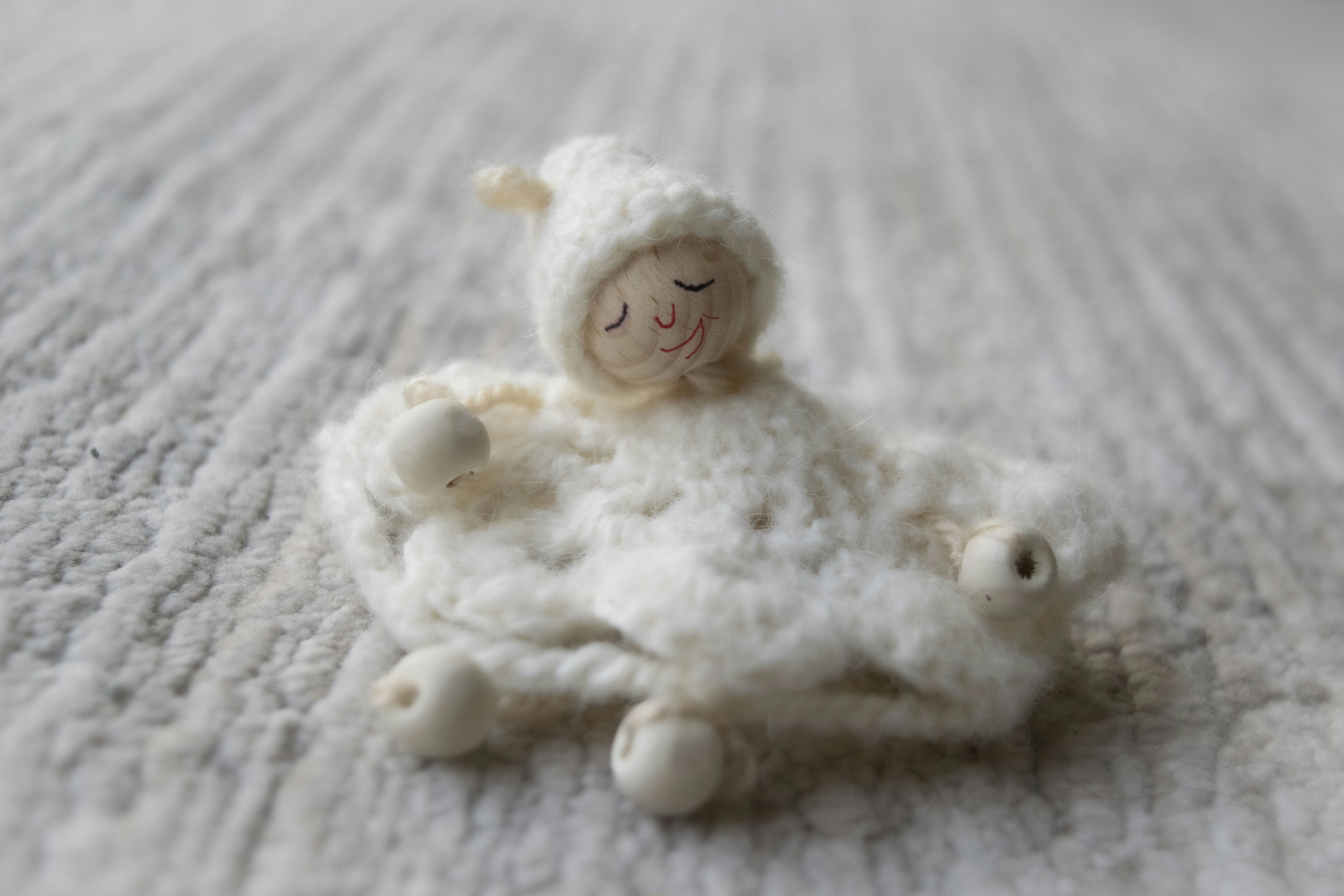 A small, crocheted sheep toy with closed eyes