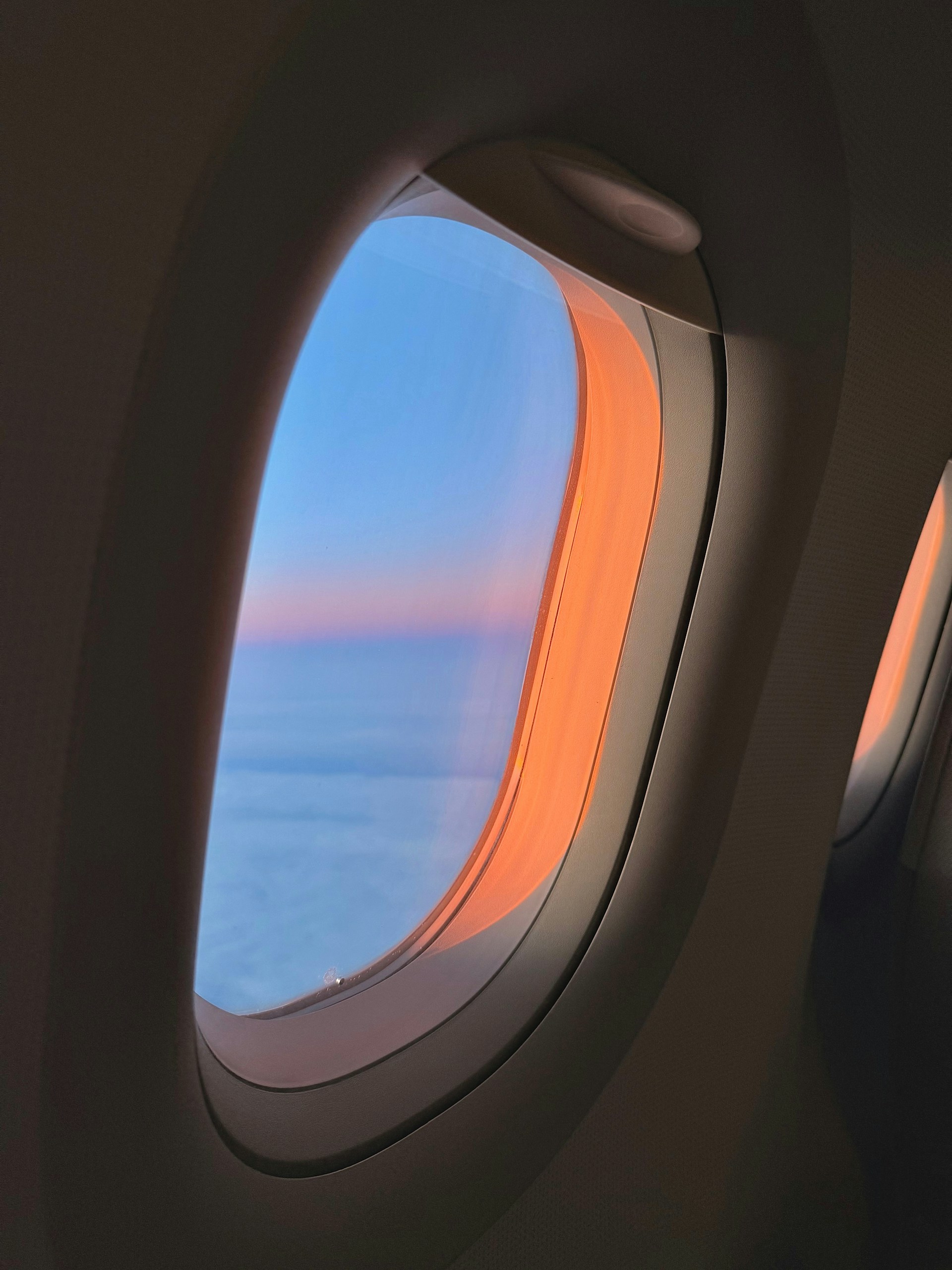 Sunset seen through an airplane window over clouds