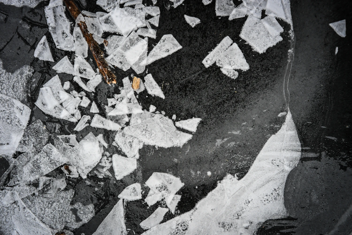 Slabs of river ice scattered across dark water after an impact