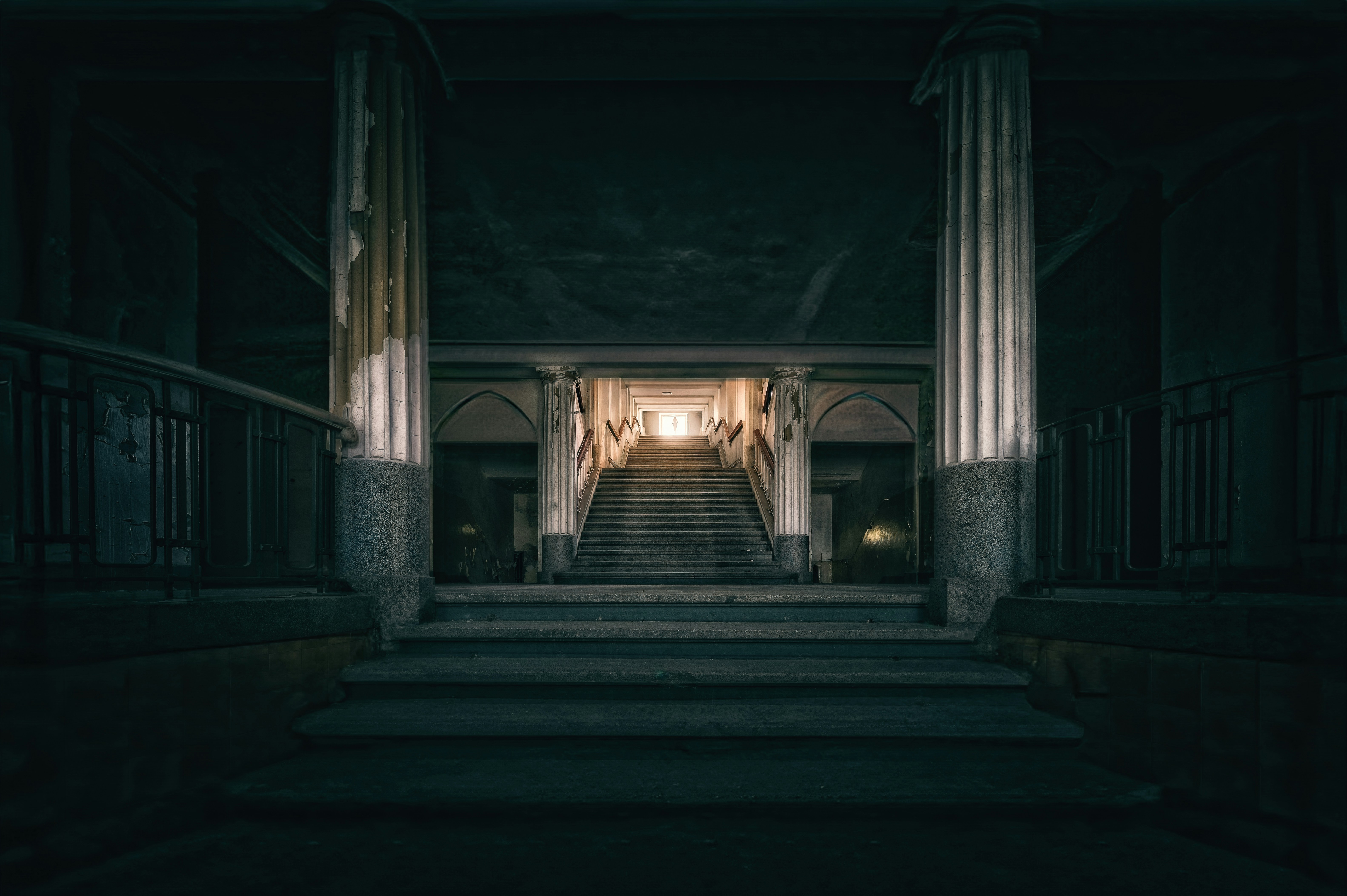 Grand staircase leading to bright light in a dark building.