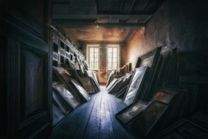 Dusty room filled with leaning framed artwork