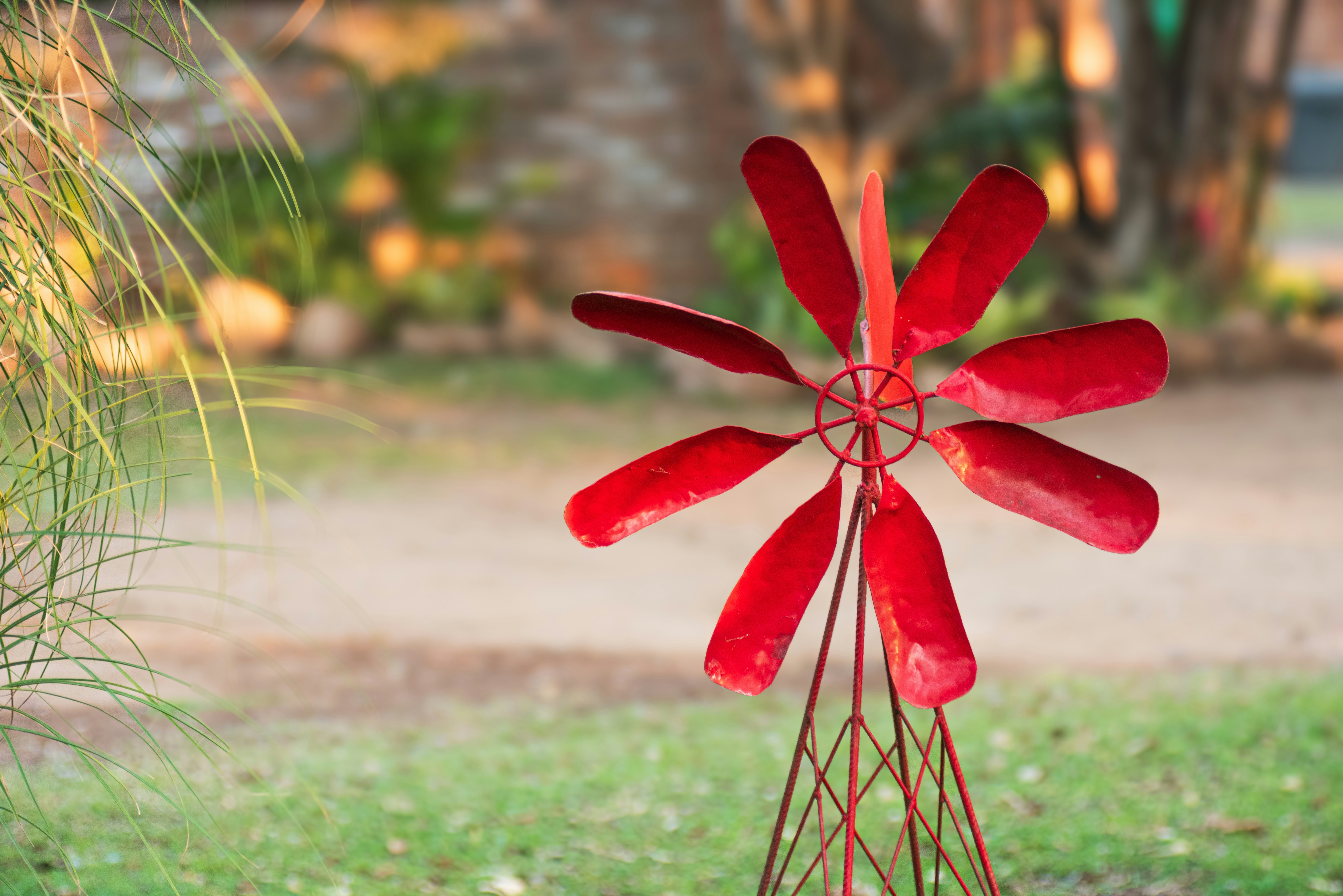 A bright red windmill stands in a grassy yard.