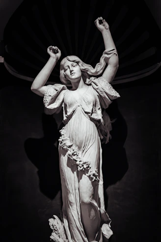 A marble statue of a woman with raised arms.