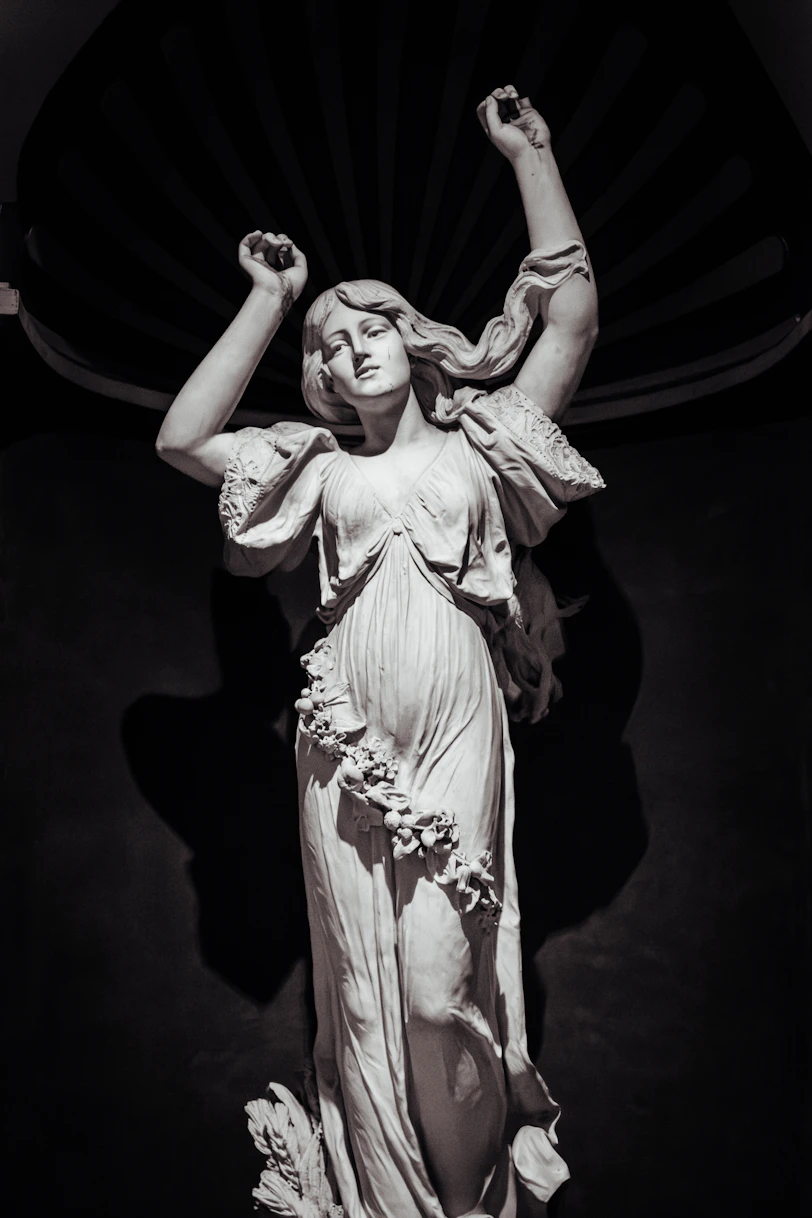 A marble statue of a woman with raised arms.