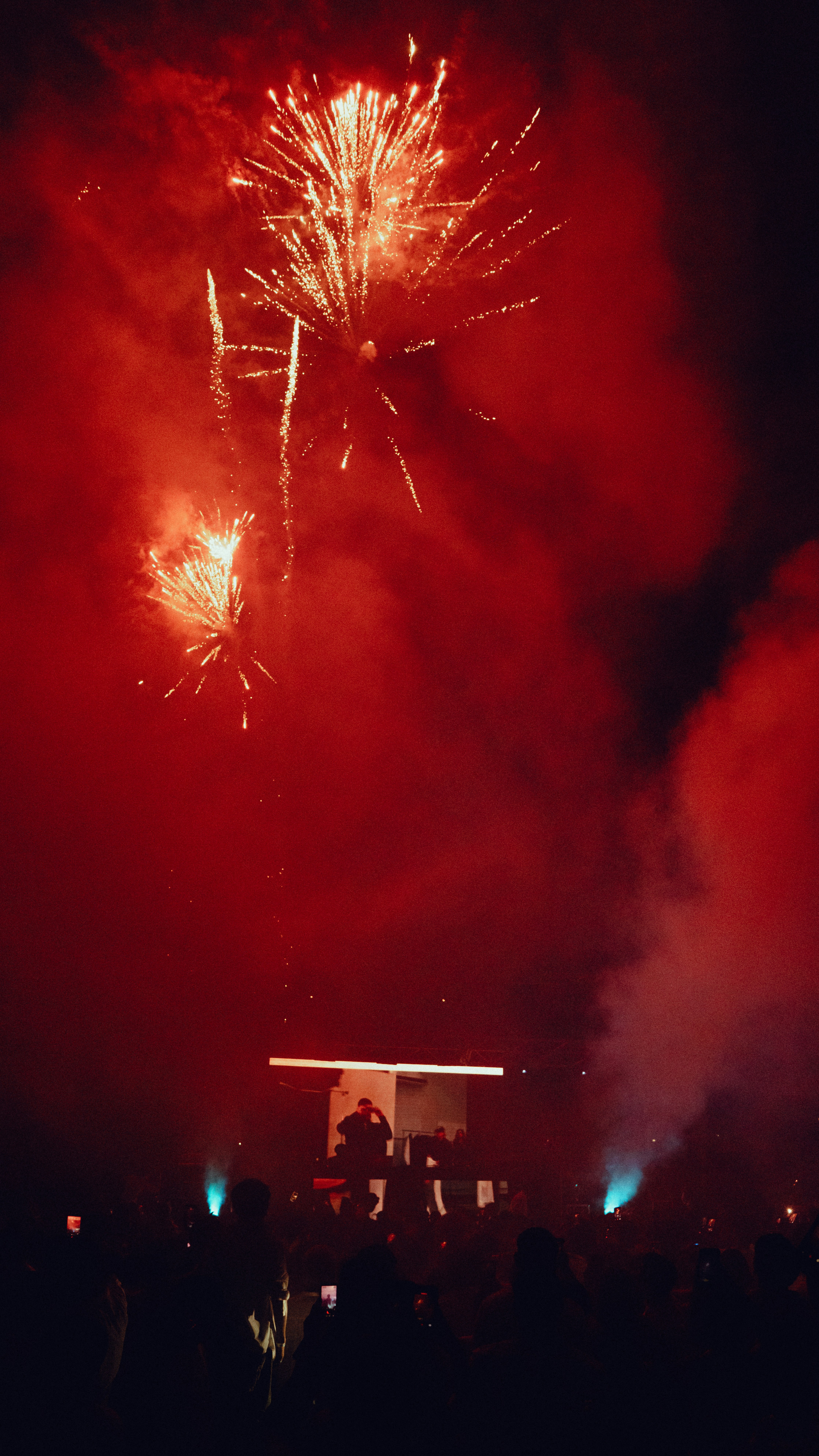 Feuerwerk explodiert über einer Menschenmenge bei einer nächtlichen Veranstaltung.