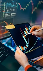 Trader analyzing stock market charts on tablet and monitor