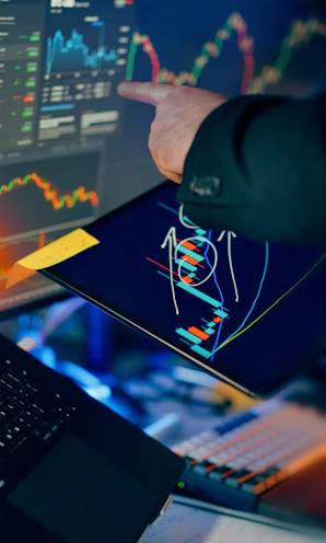 Trader analyzing stock market charts on multiple screens.