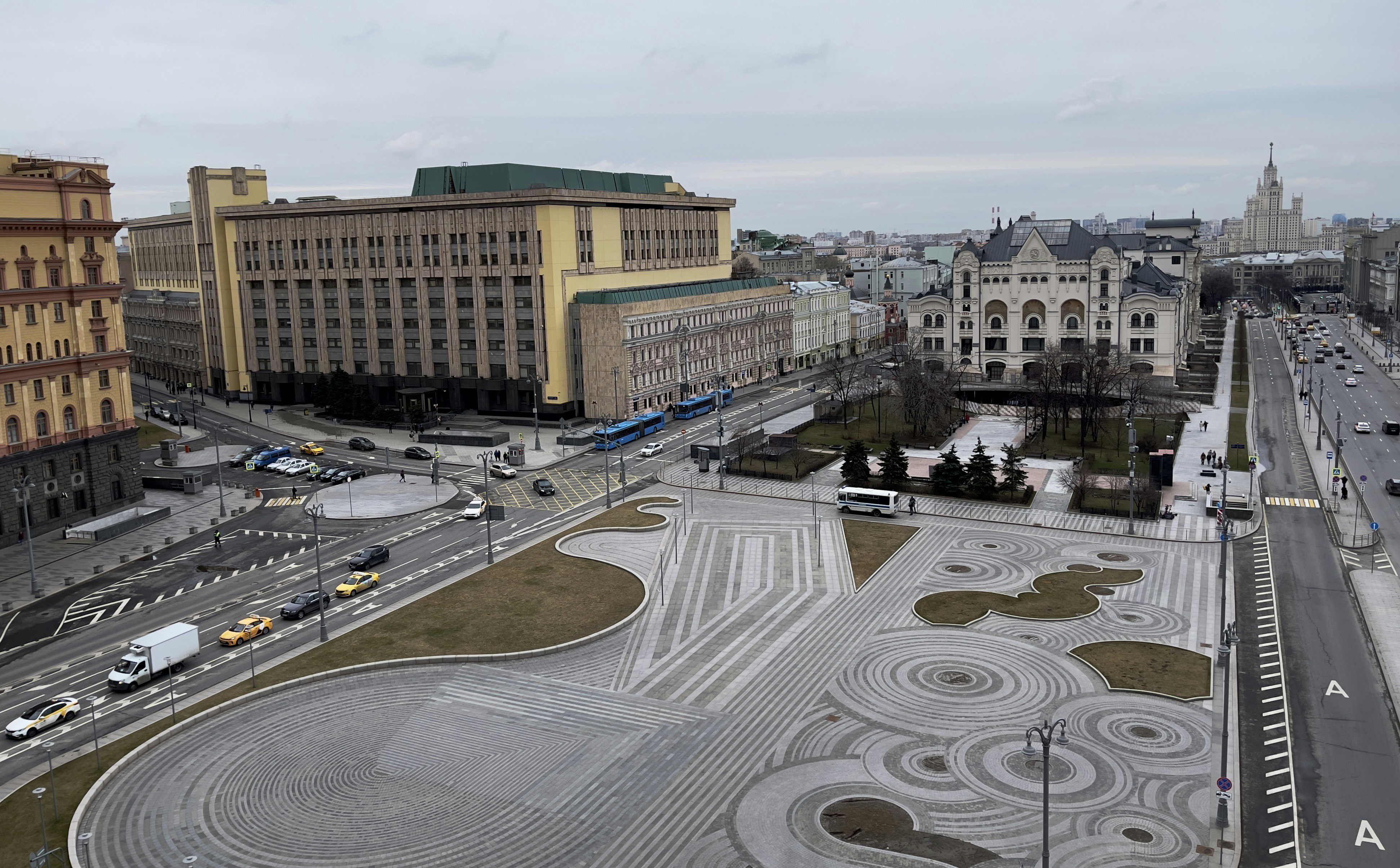 Vue large sur une place de la ville avec des bâtiments et de la circulation.