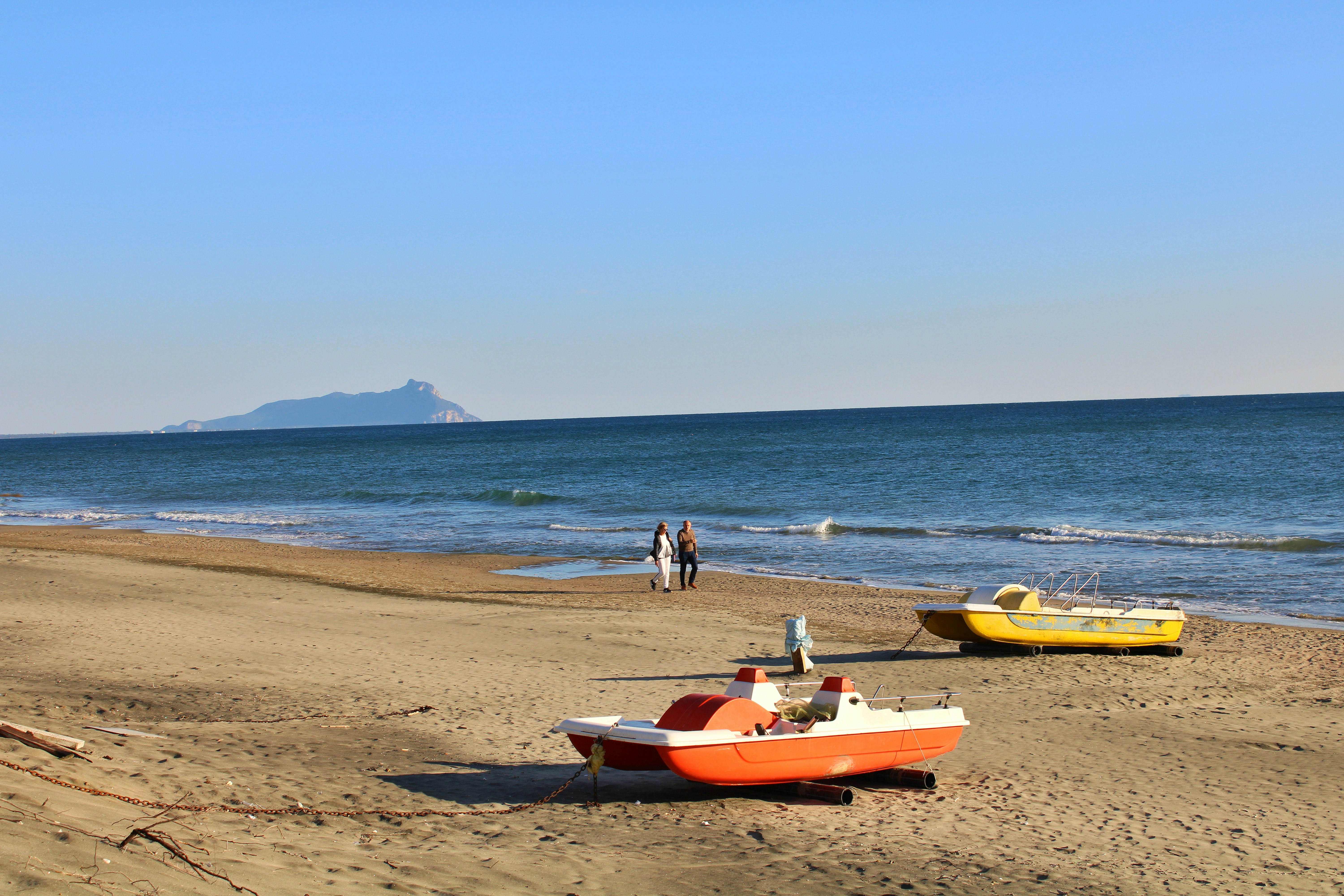 Zwei Tretboote an einem Sandstrand mit Ozeanhintergrund.