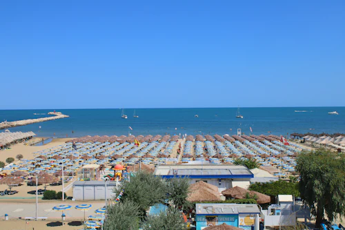 Lang zandstrand vol rijen parasols, kalme blauwe zee