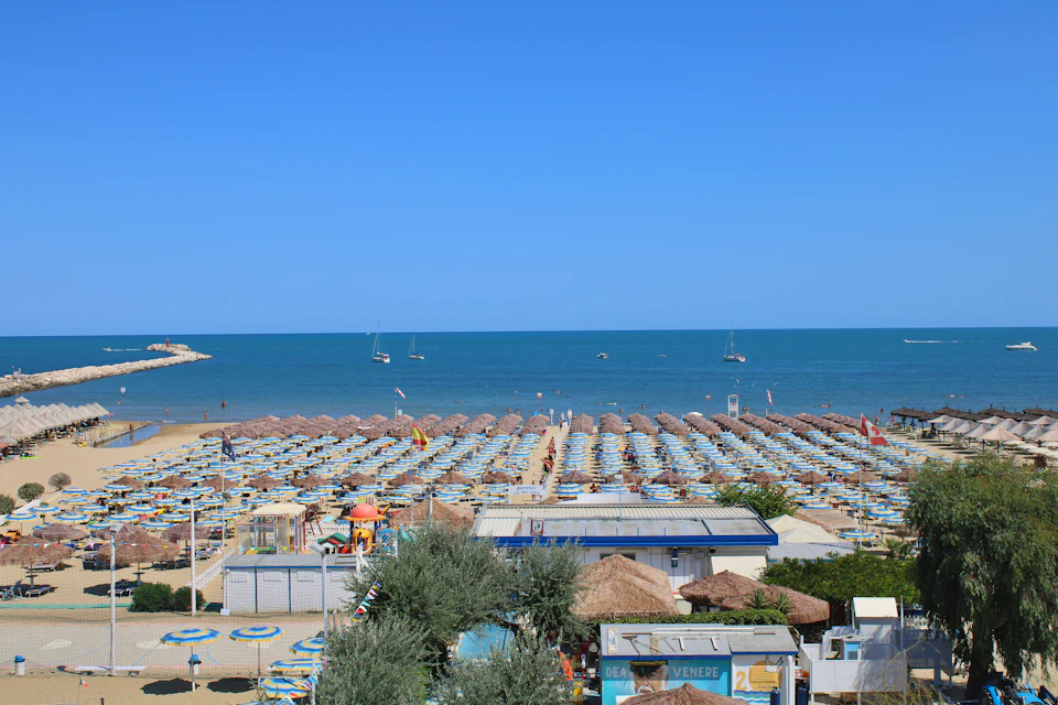 Lang zandstrand vol rijen parasols, kalme blauwe zee