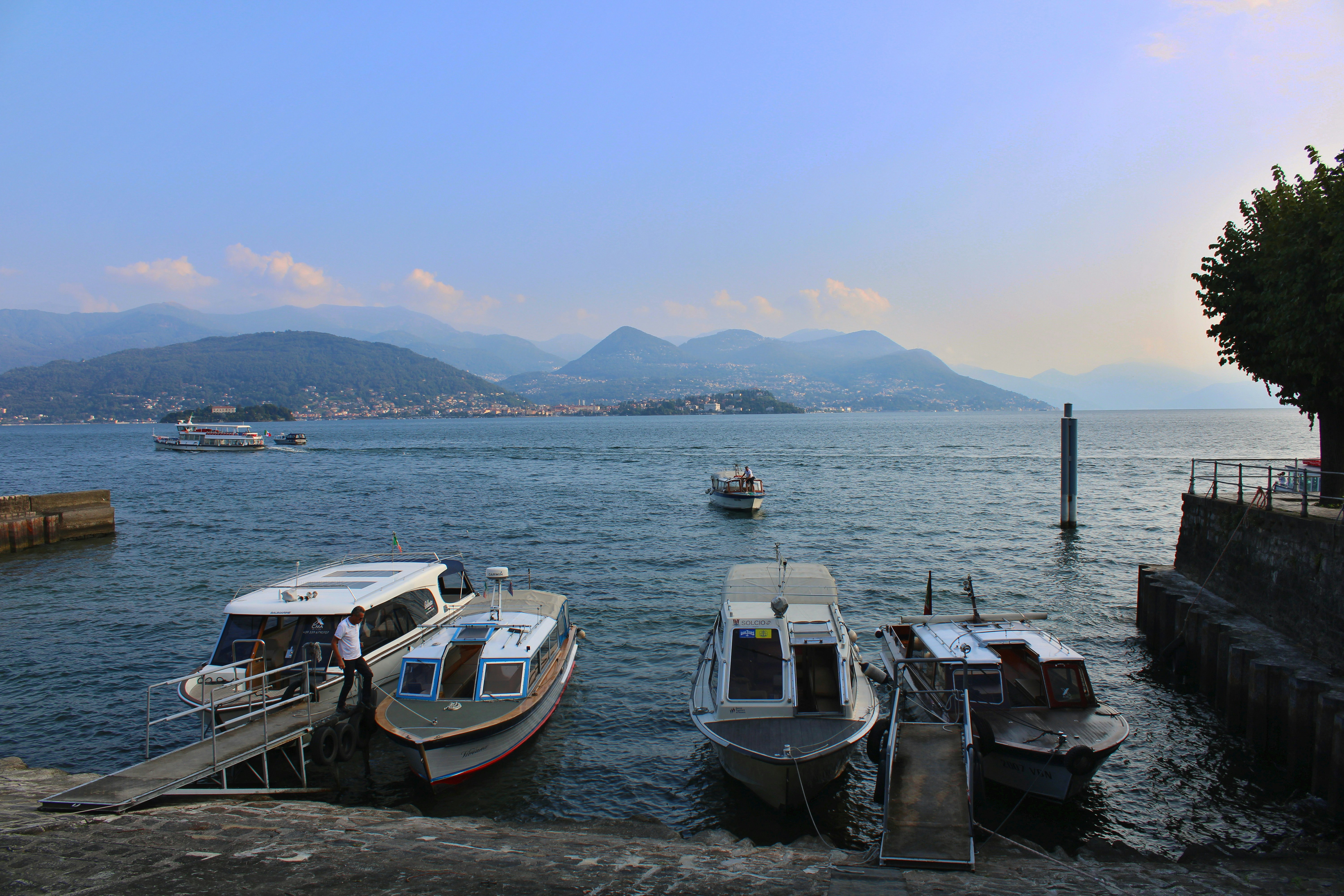 Boats docked on a calm lake with distant mountains.
