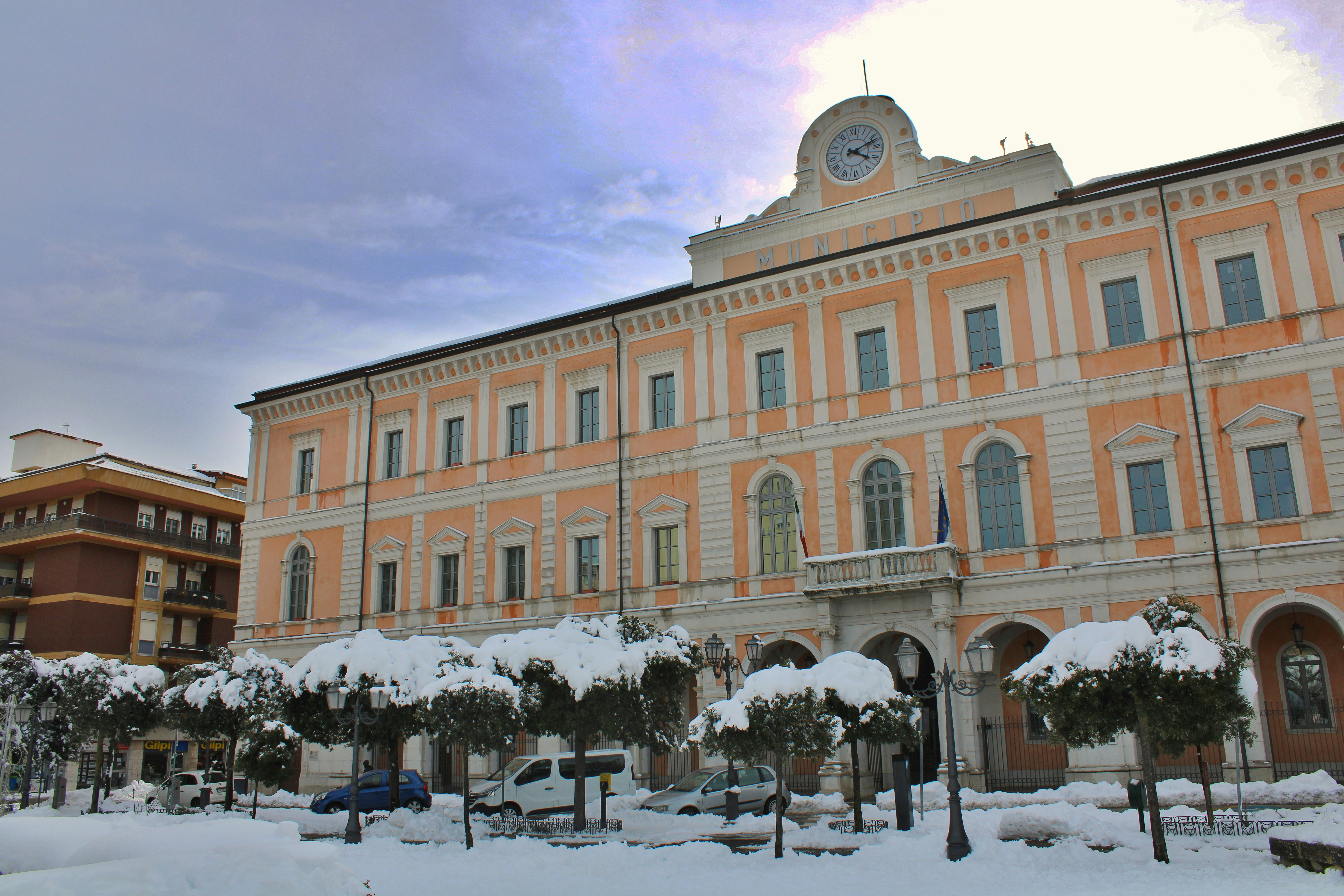 Large building covered in snow with bare trees