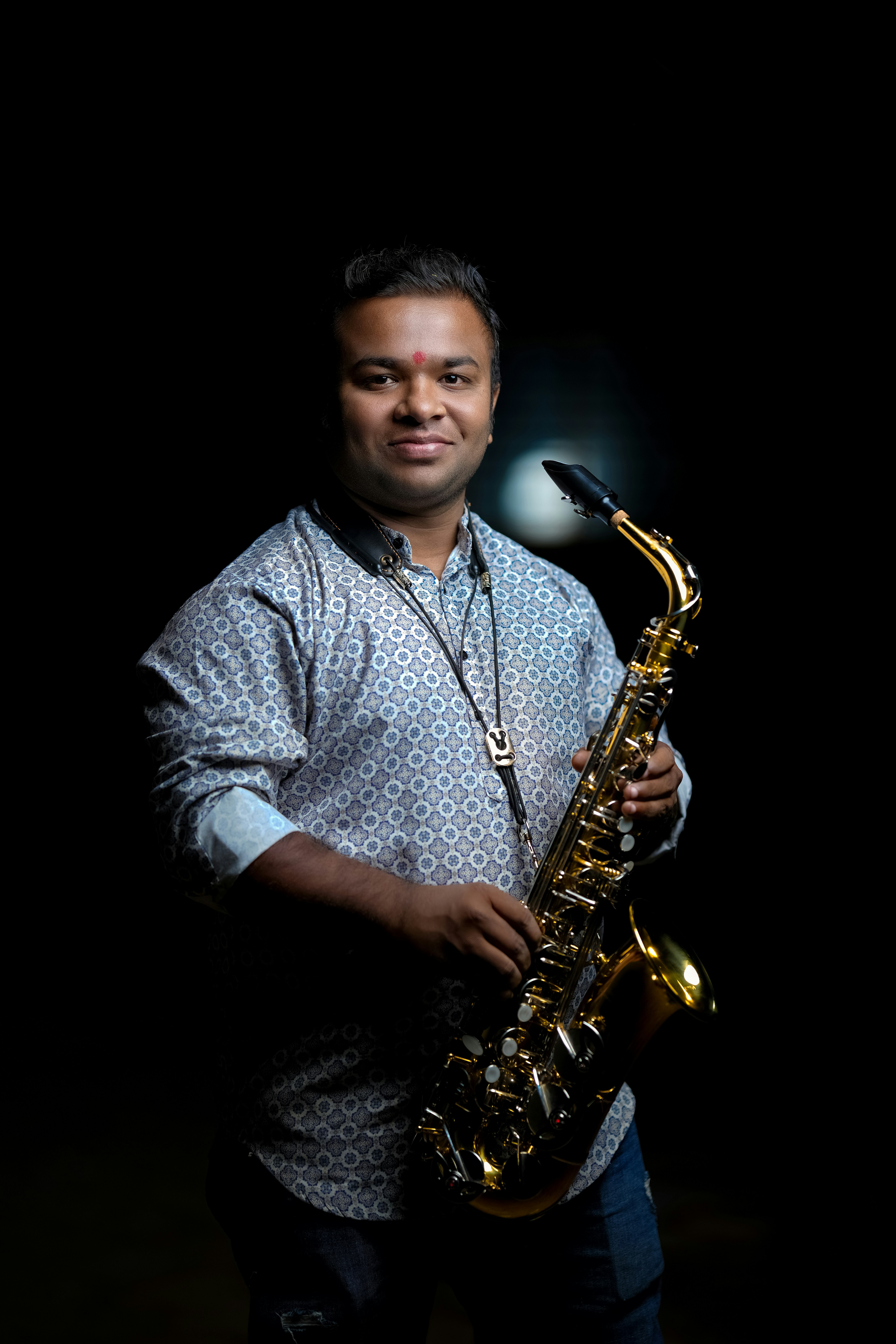 Man holding a saxophone against a dark background
