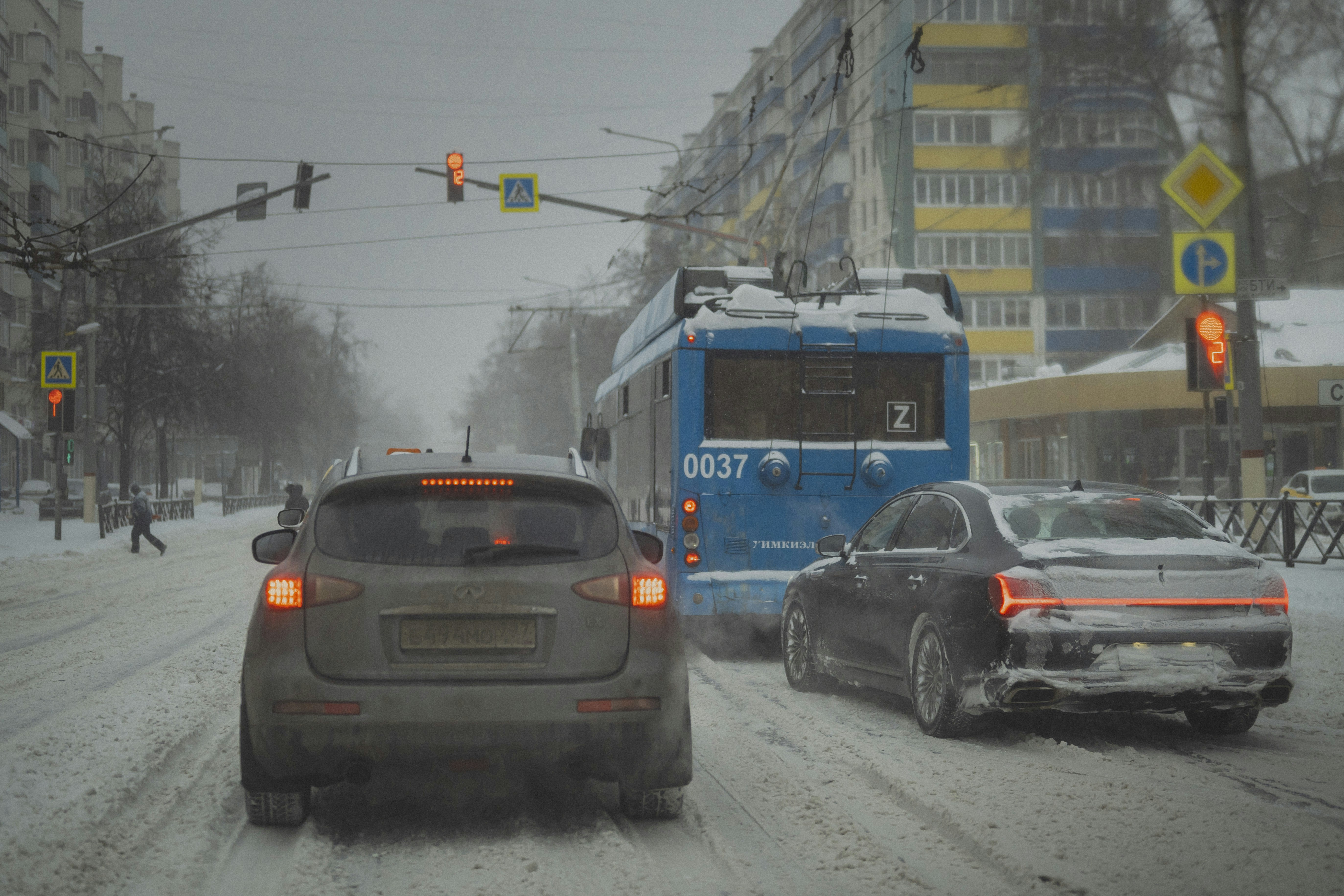 Autos fahren tagsüber auf einer verschneiten Stadtstraße.