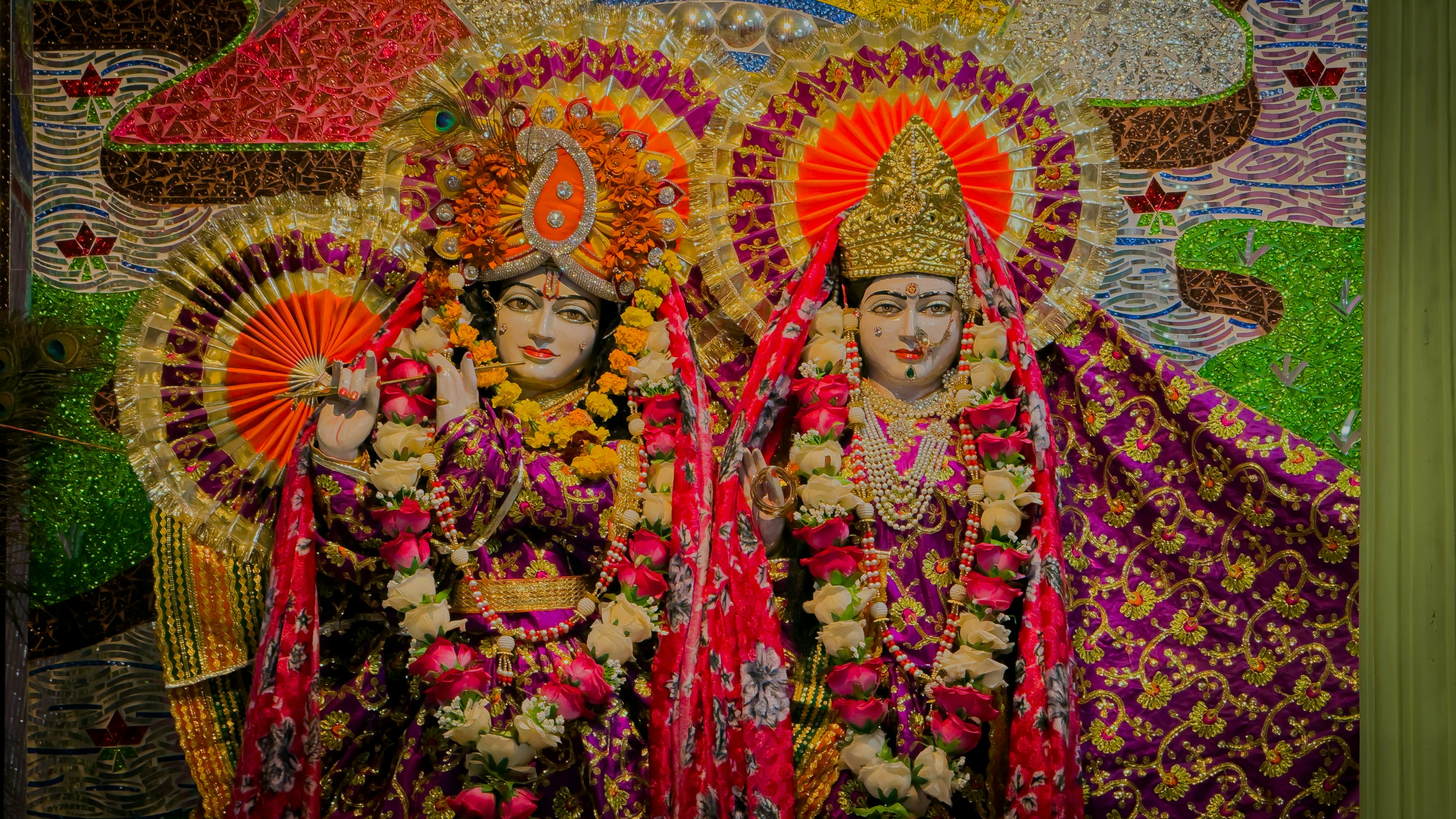 Two ornate statues of hindu deities adorned with flowers