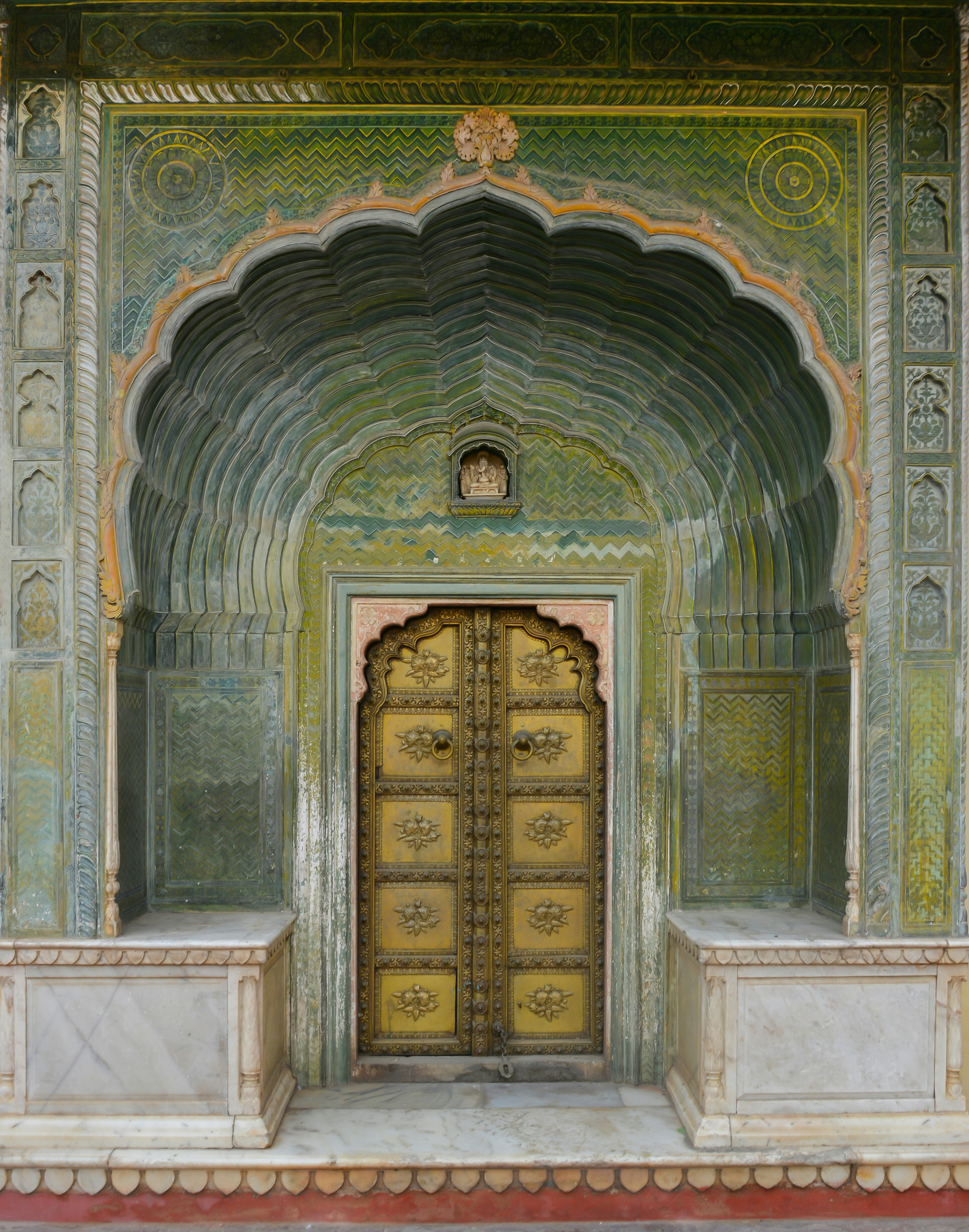 Ornate golden door set within a green arched entryway