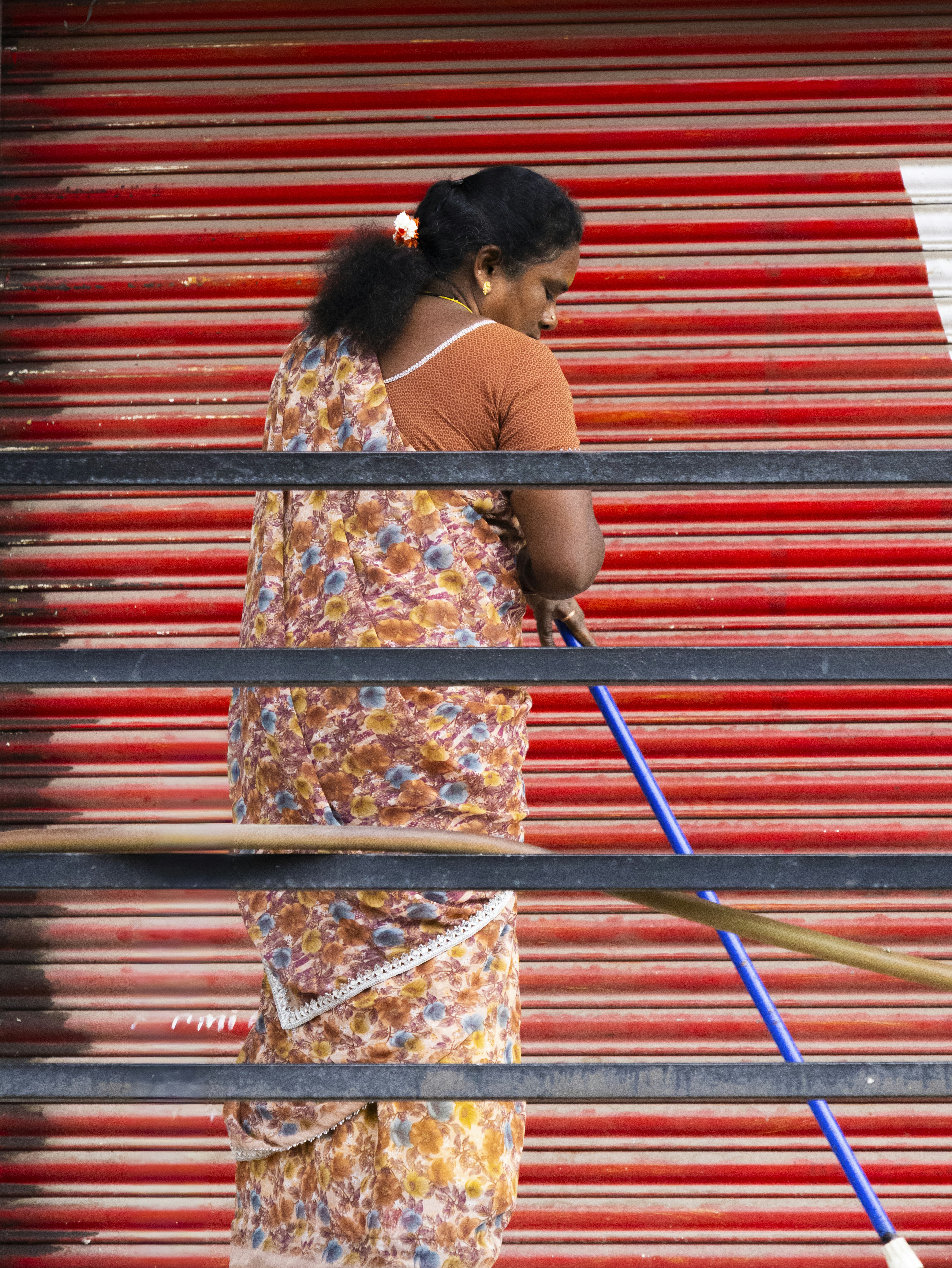 Woman in sari sweeping with a mop.