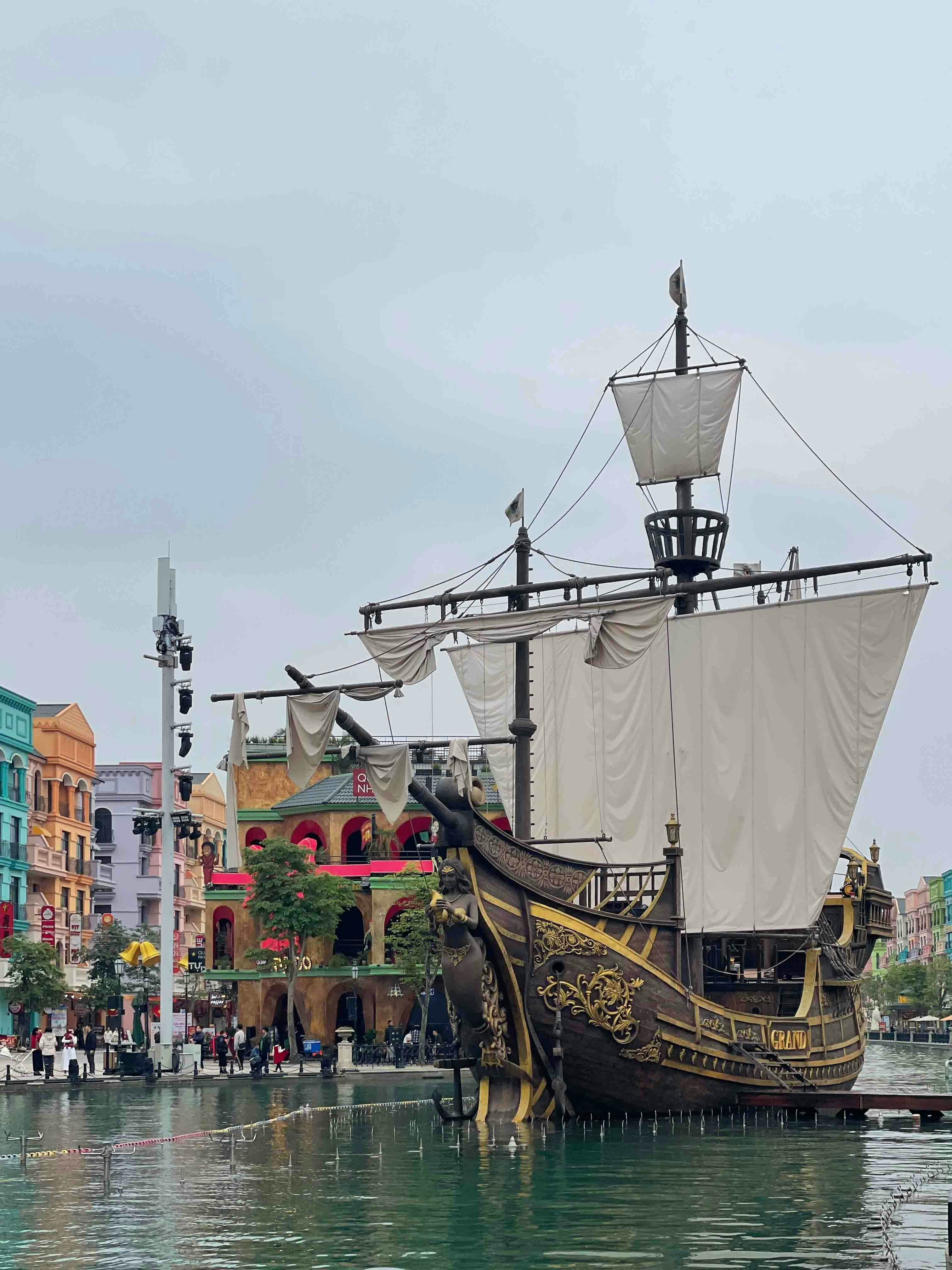 A large wooden pirate ship docked near colorful buildings.