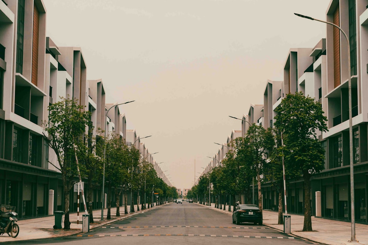 Symmetrical street lined with modern buildings and trees.