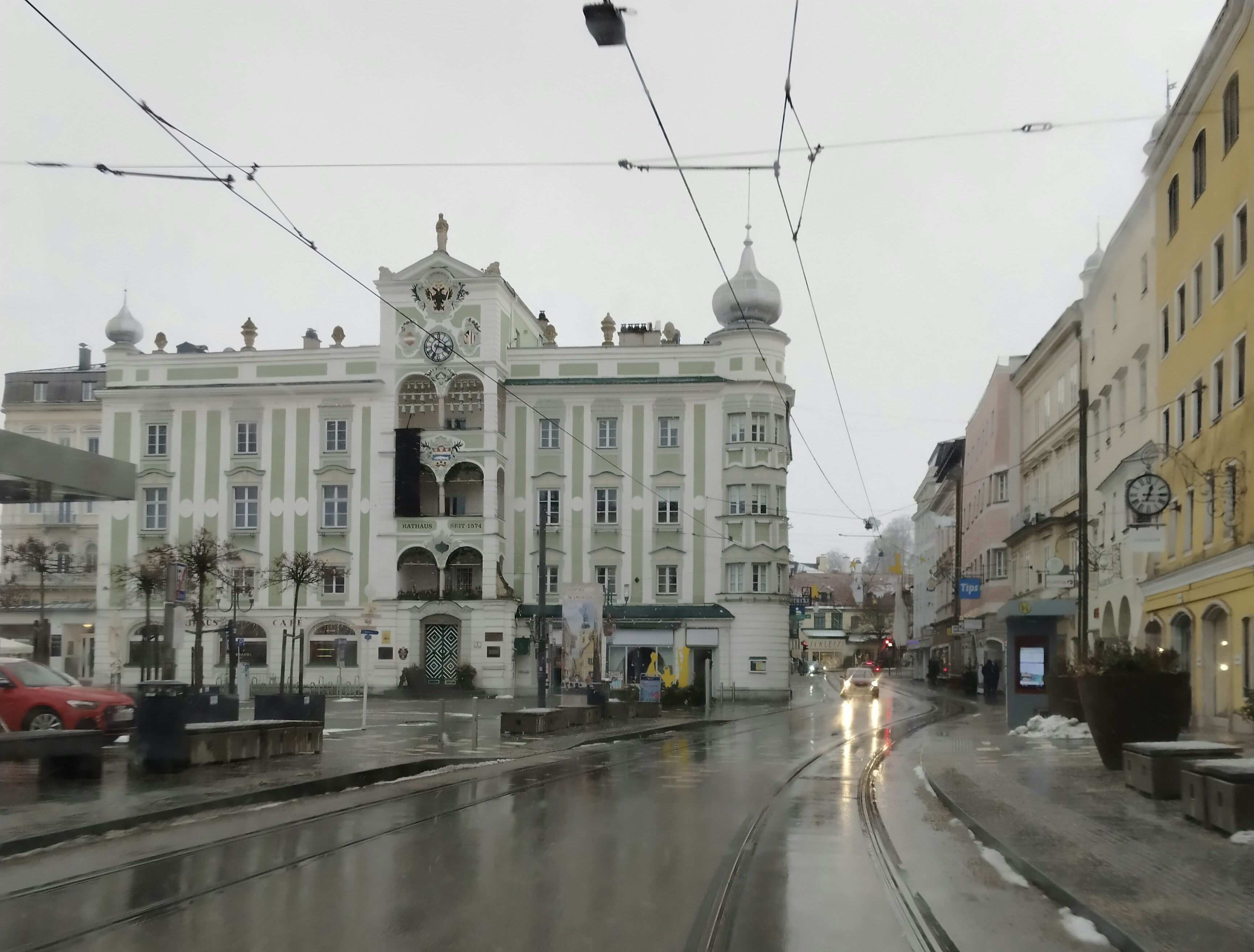 A wet city street with historic buildings and tram tracks.