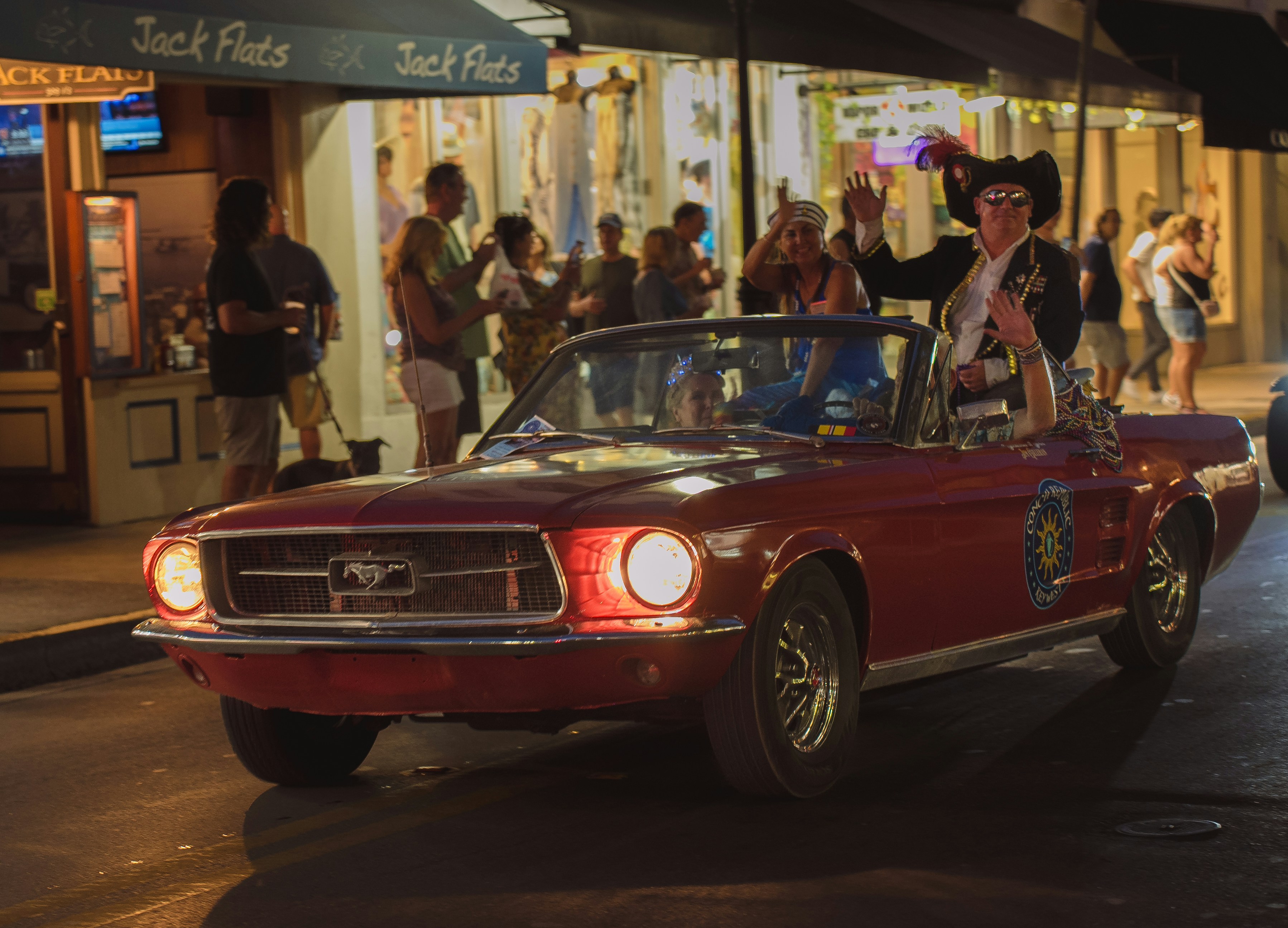 Man in pirate costume drives red convertible at night