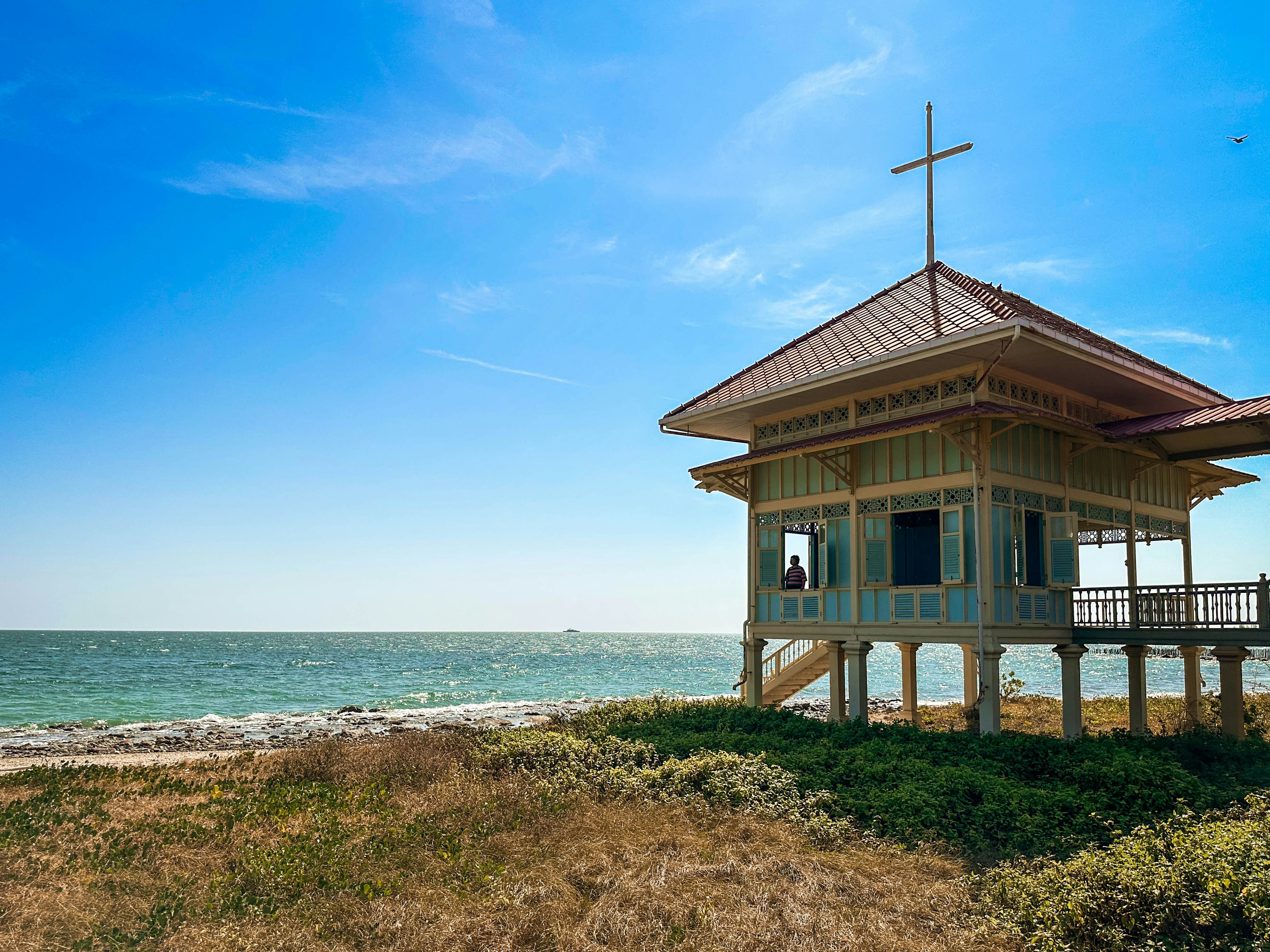 A historic pavilion on a sandy beach by the sea.