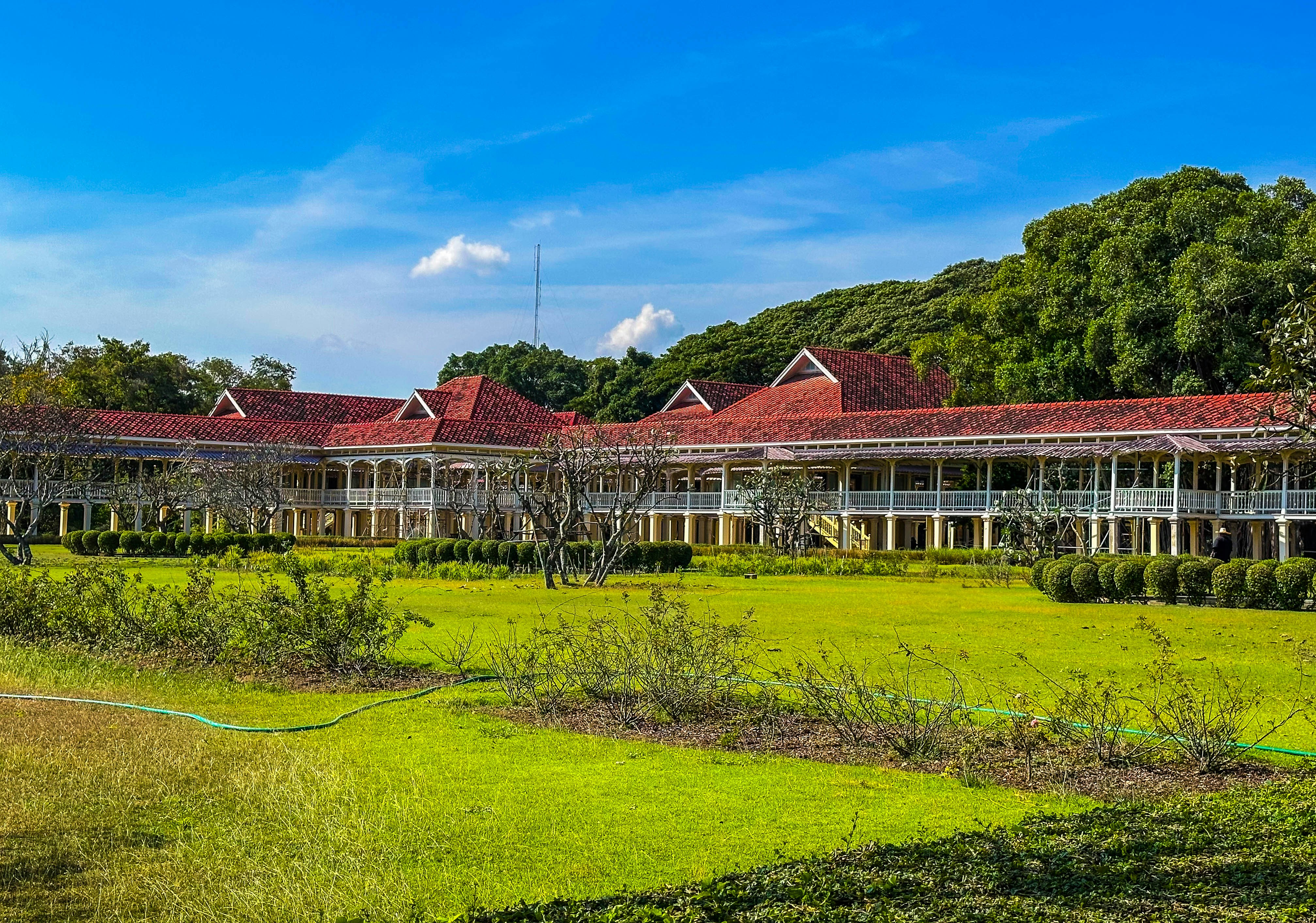 Long colonial building with red roof and green lawn.