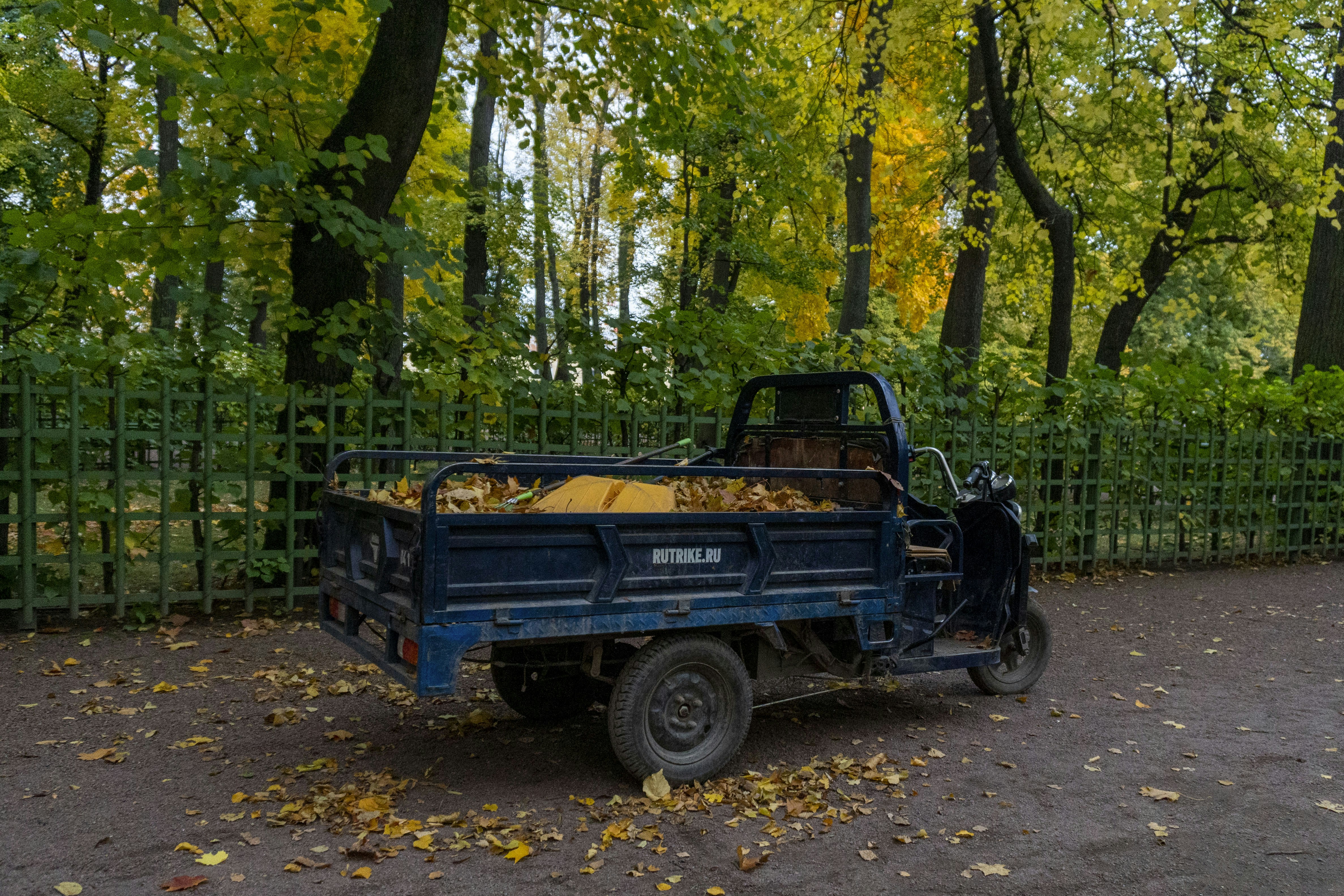 A blue three-wheeled truck filled with sand in autumn park