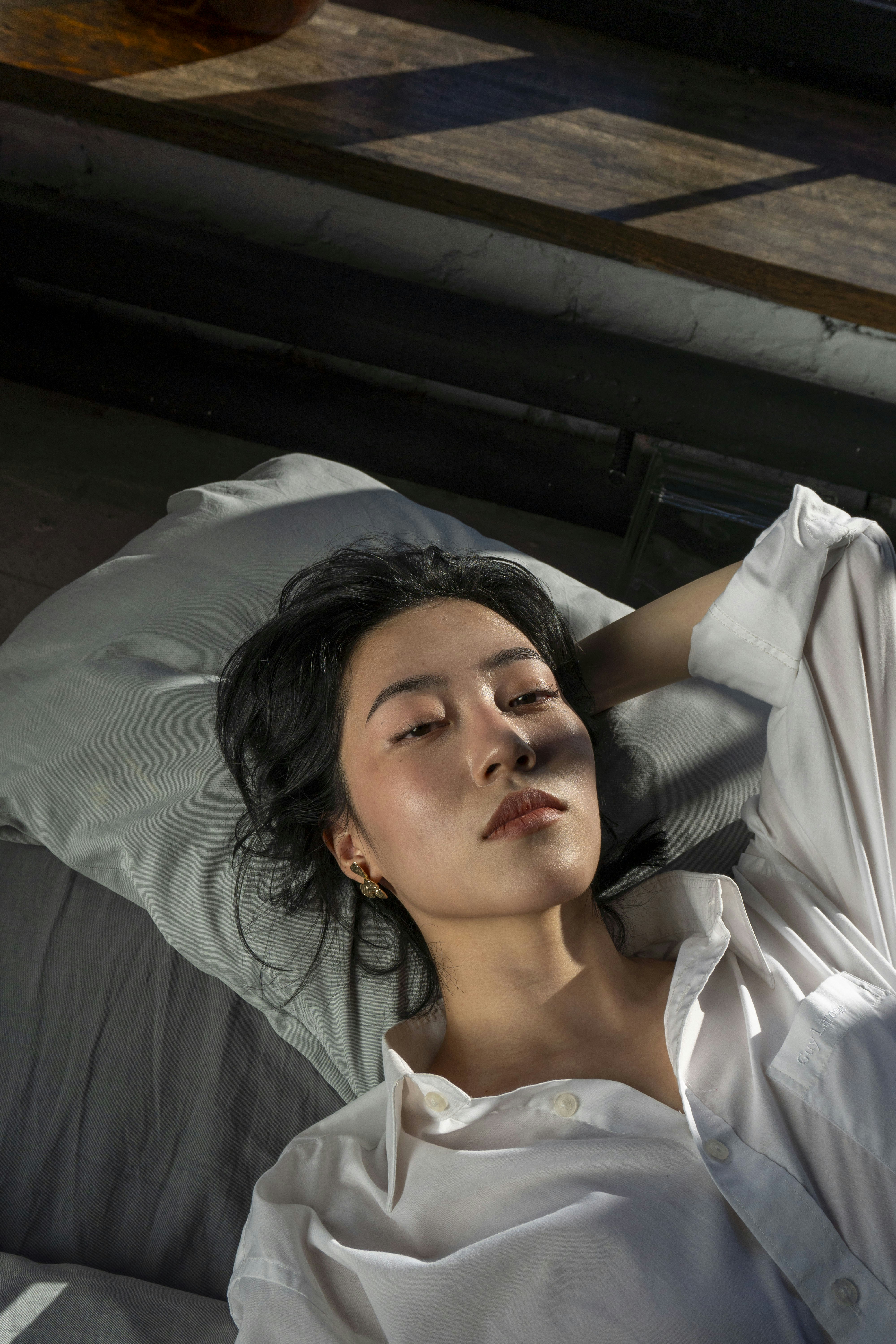 Young woman lying on a pillow with sunlight on face.