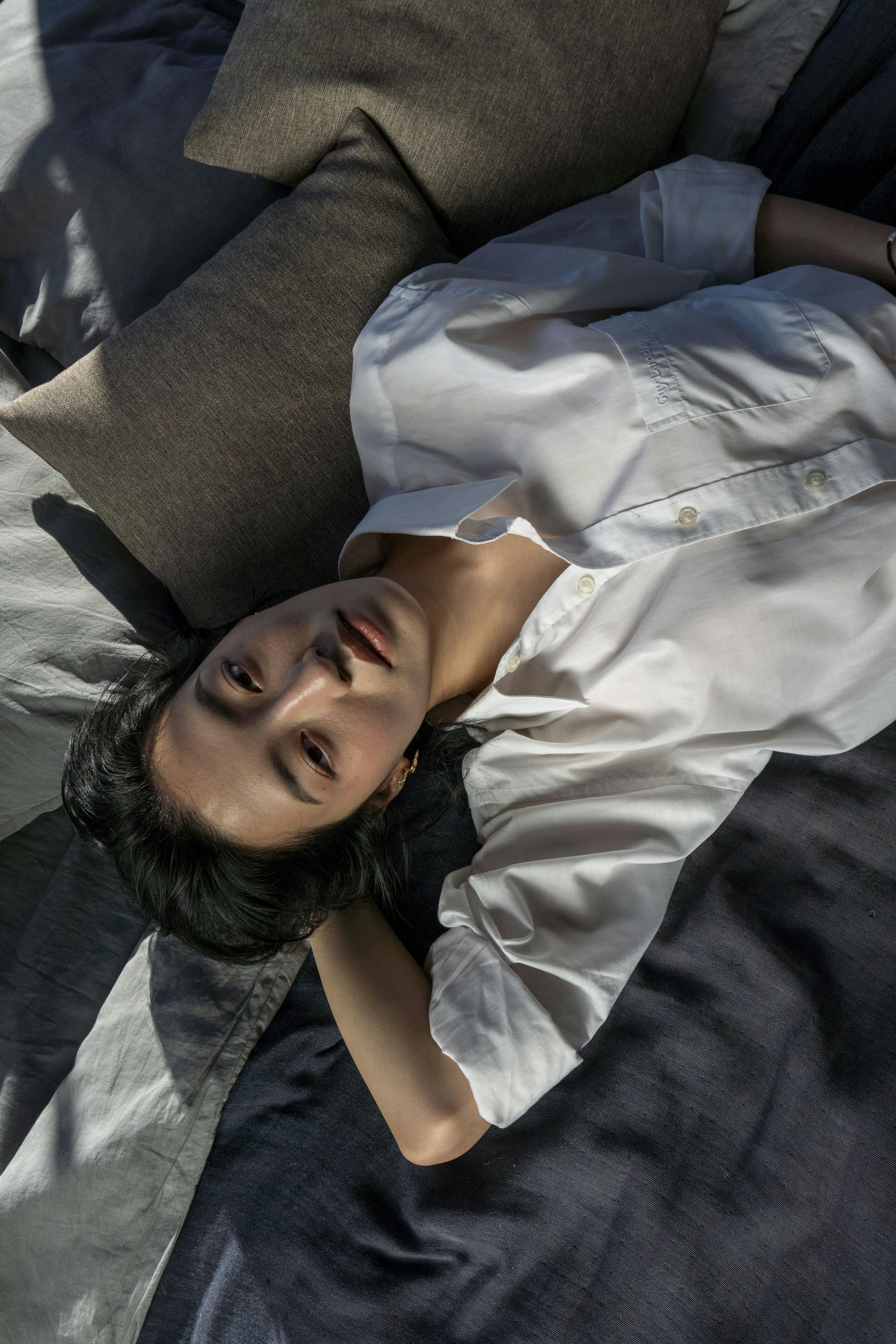 A woman in a white shirt lies on a bed.