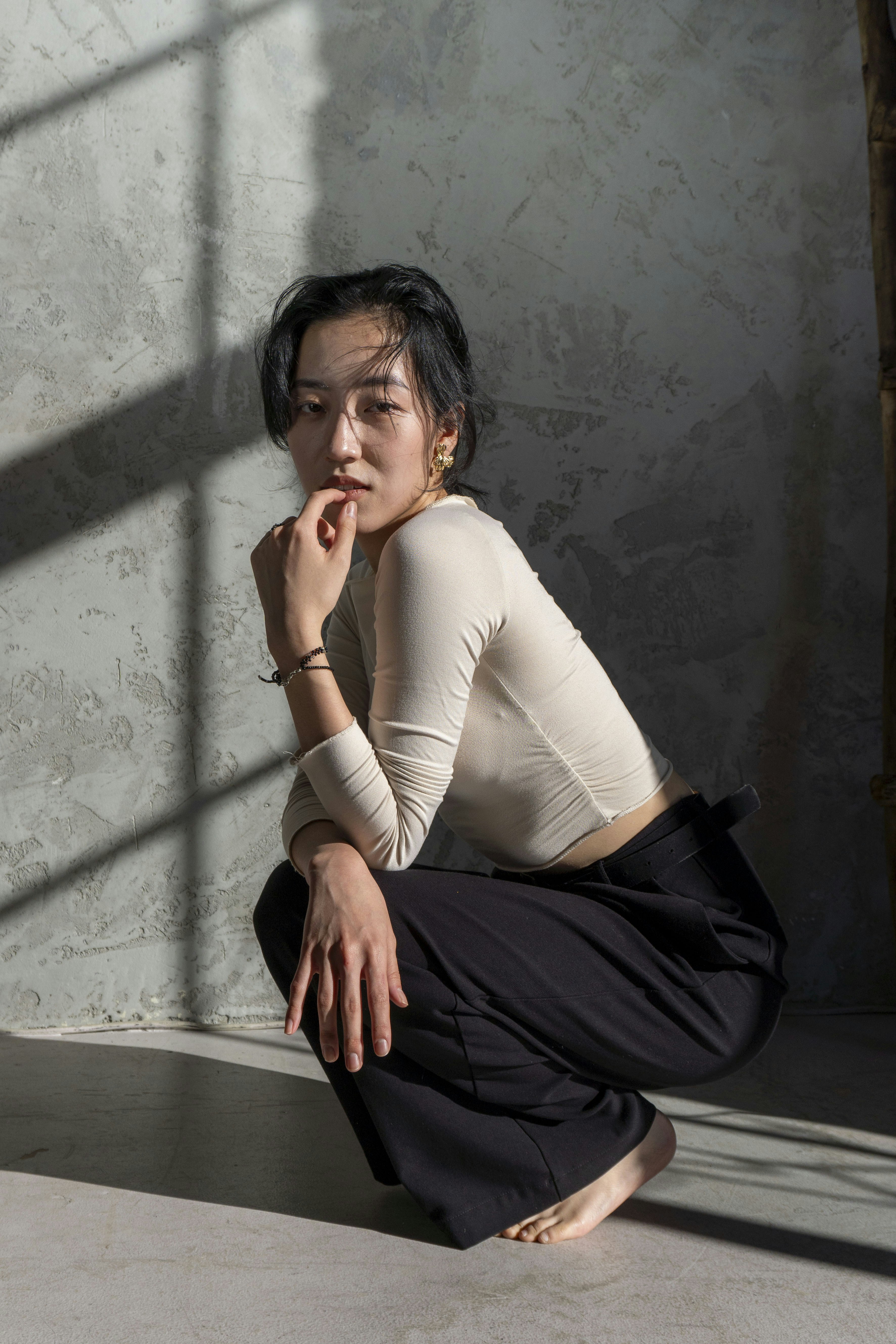 A woman squats in a long-sleeved shirt and pants.