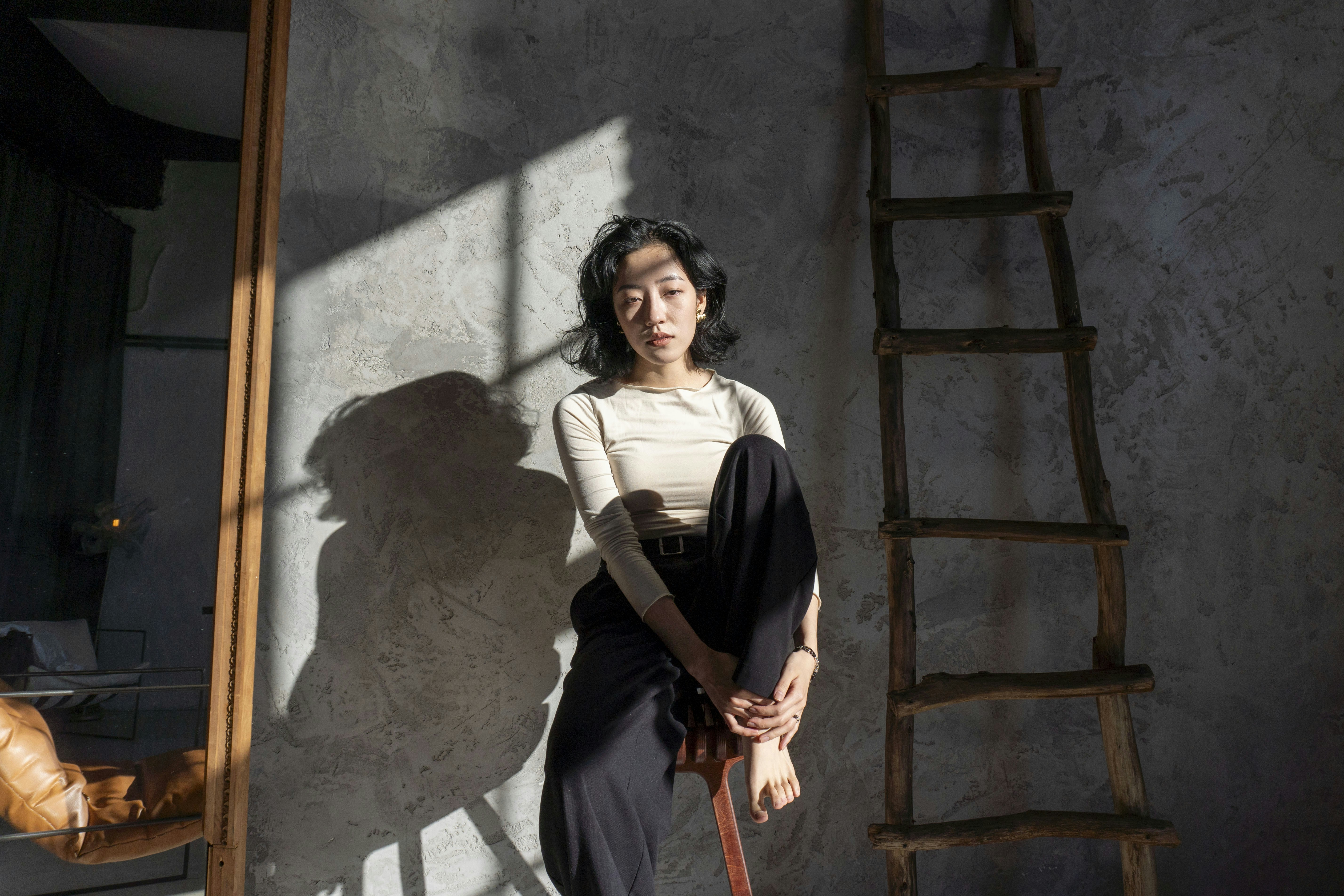 Woman sitting in a room with dramatic light and shadows.