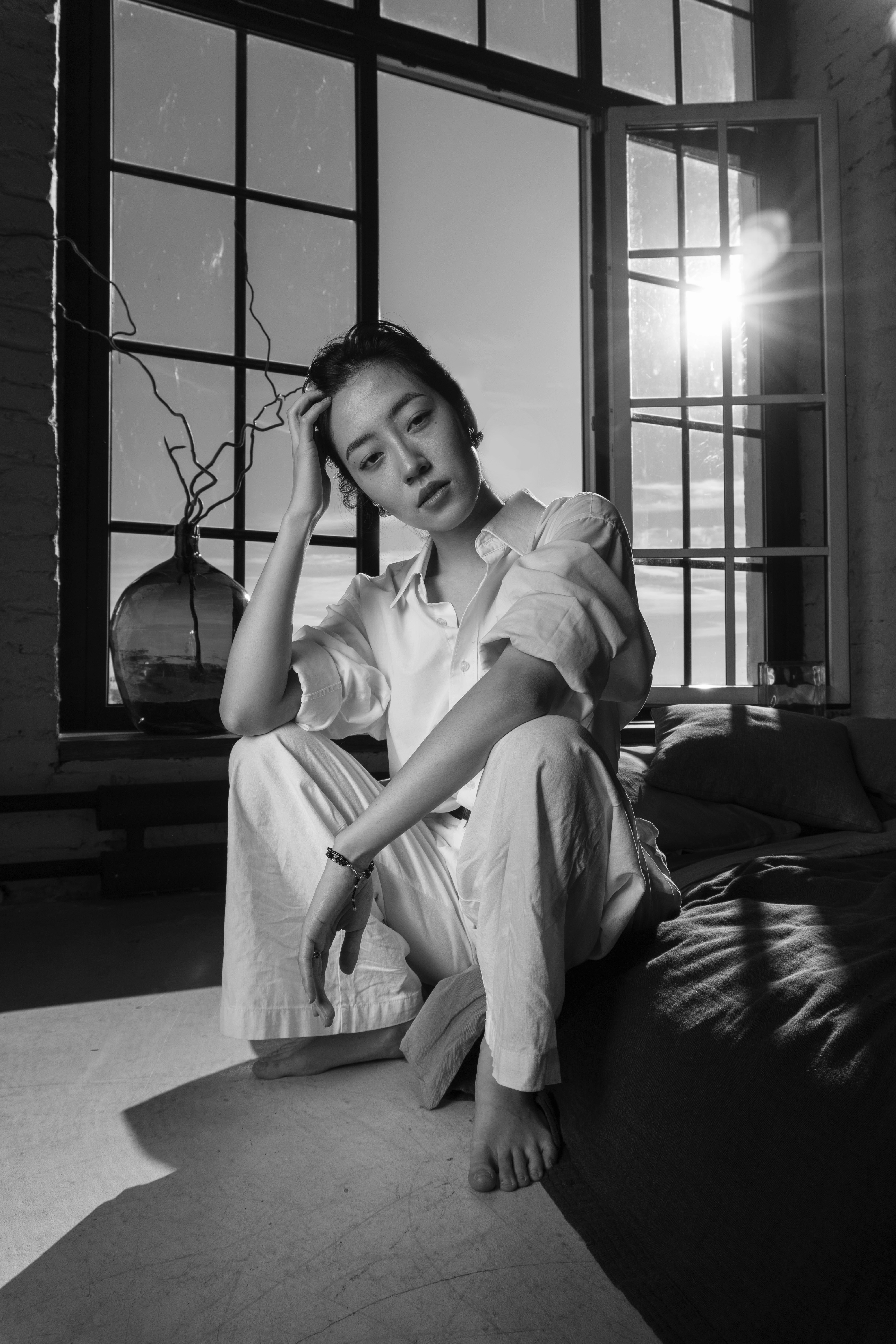 Woman sitting on bed near large window