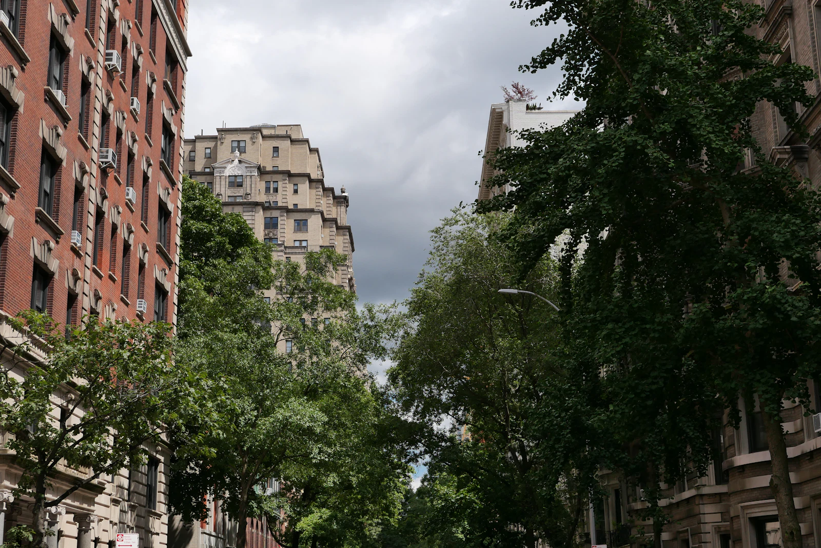 Older brick apartment buildings behind mature trees.