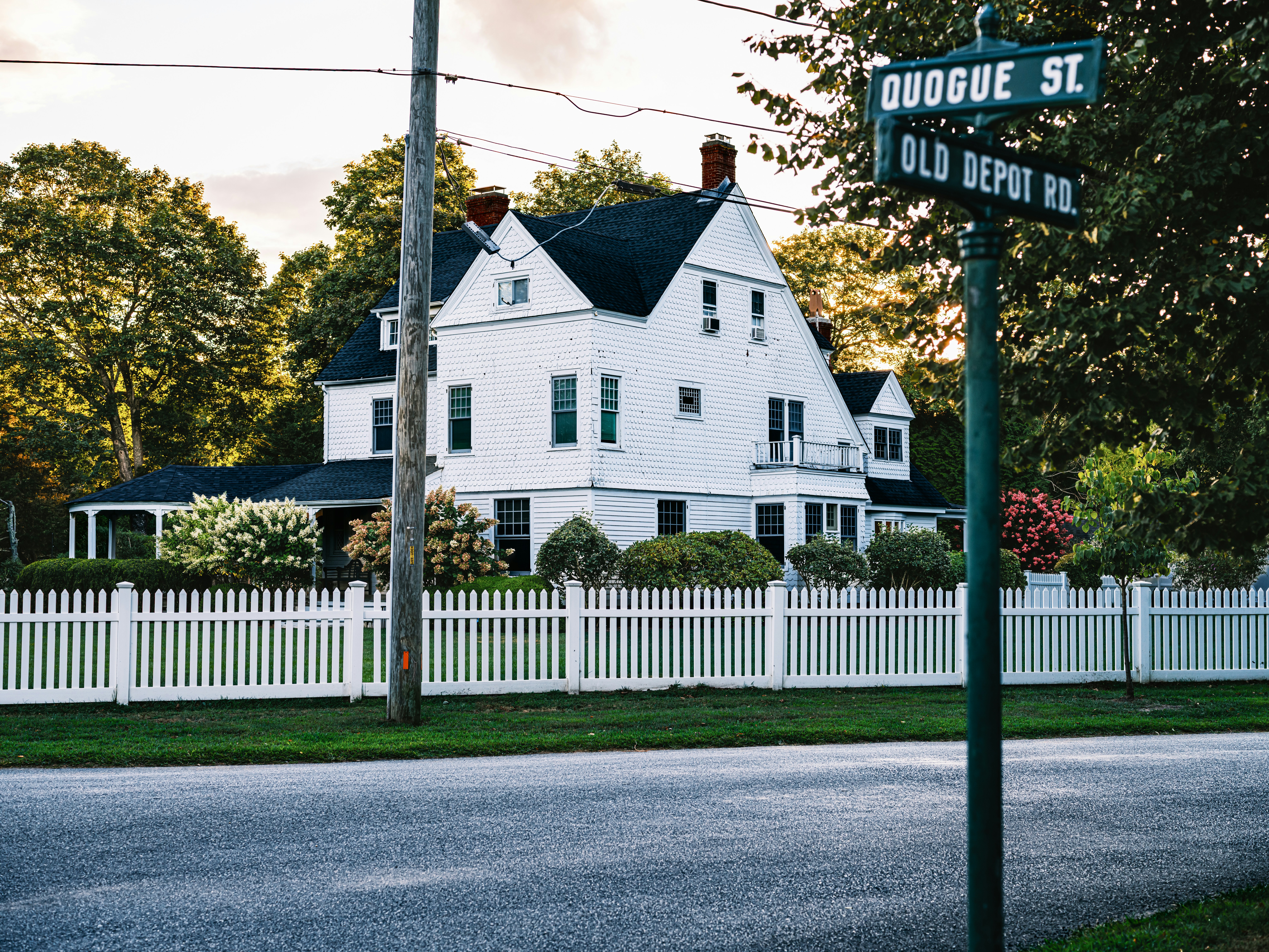 White house with picket fence and street signs