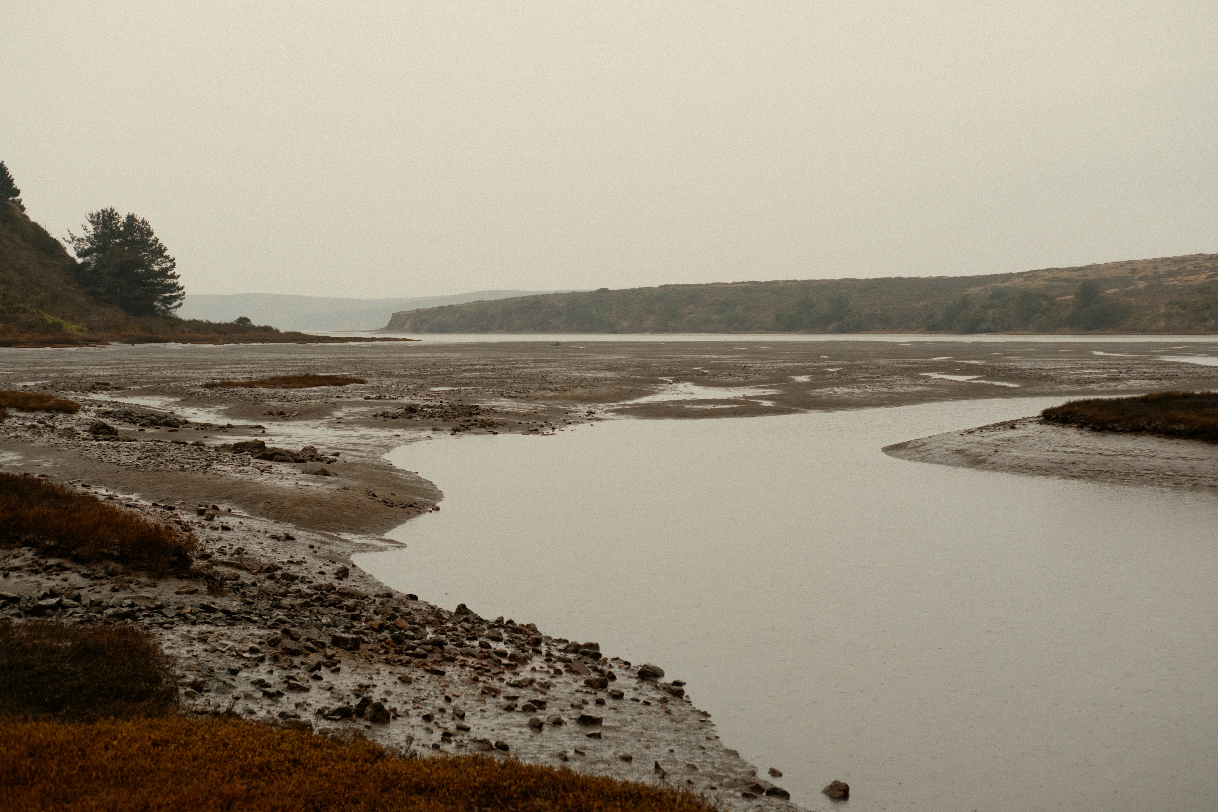 A calm river flows through a misty landscape.