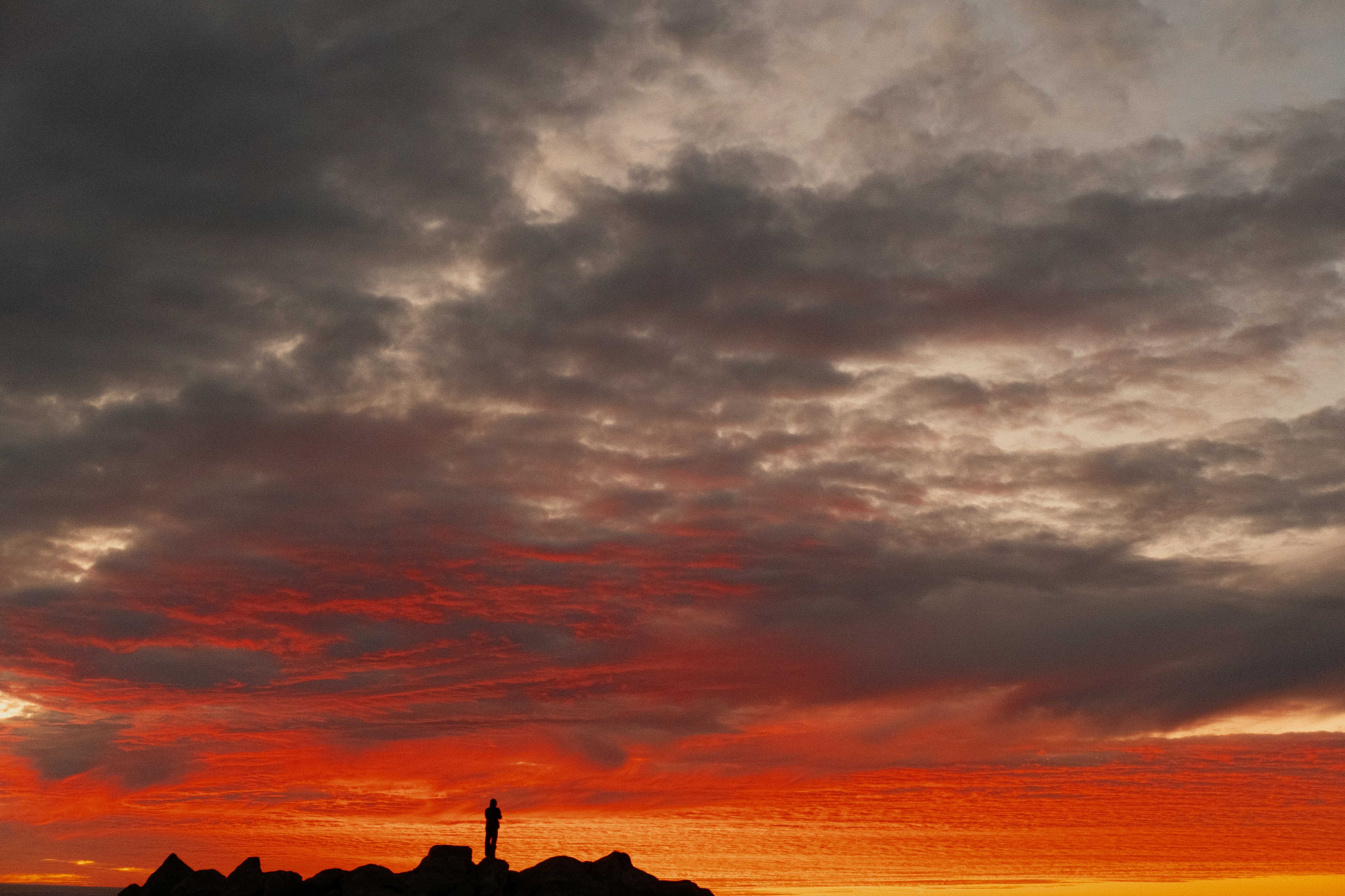 Dramatic sunset sky with silhouetted buildings below.