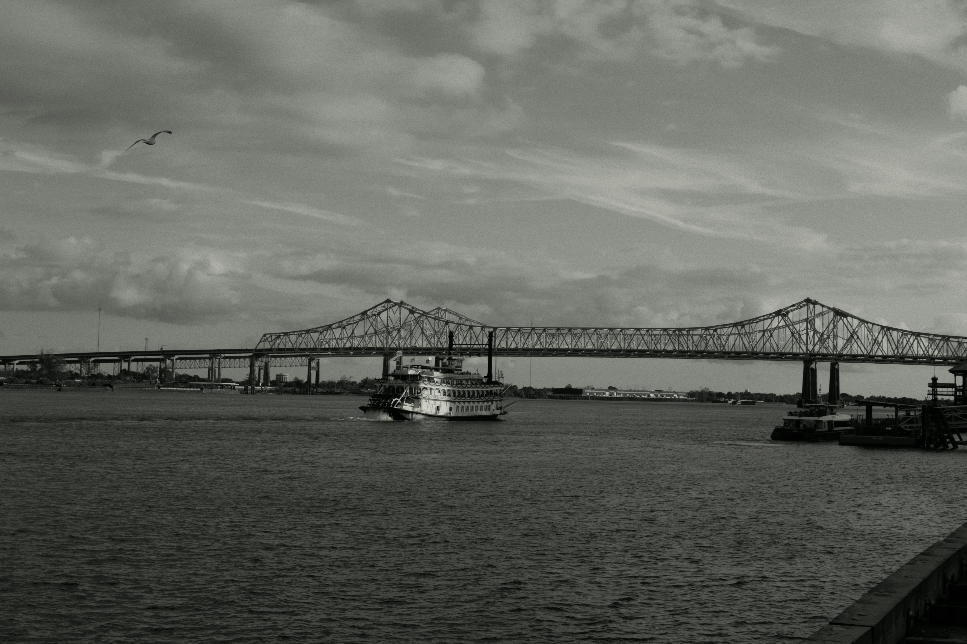 A large bridge spans a wide river with boats.