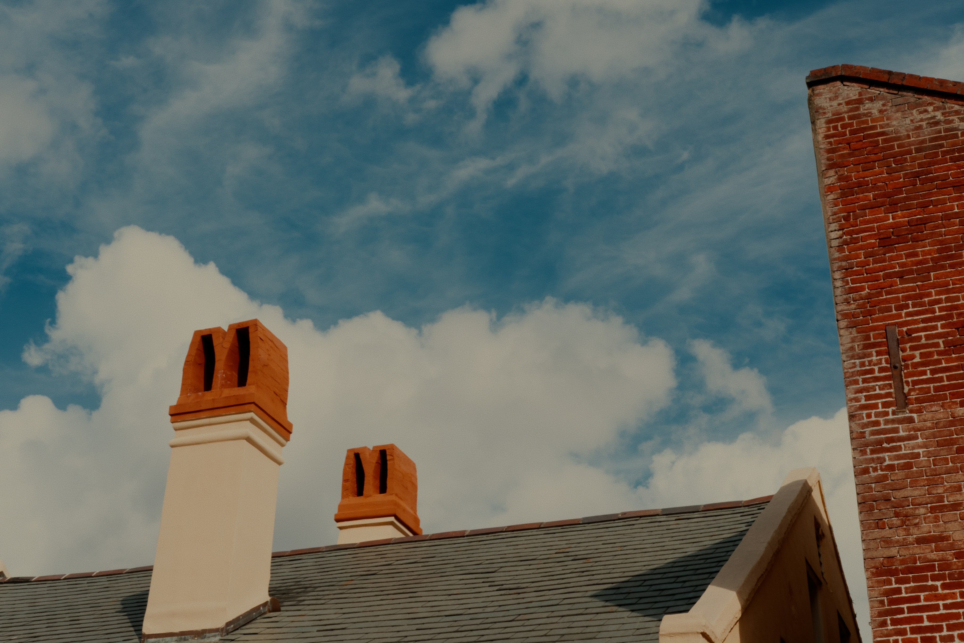 Two chimneys on a rooftop under a cloudy sky