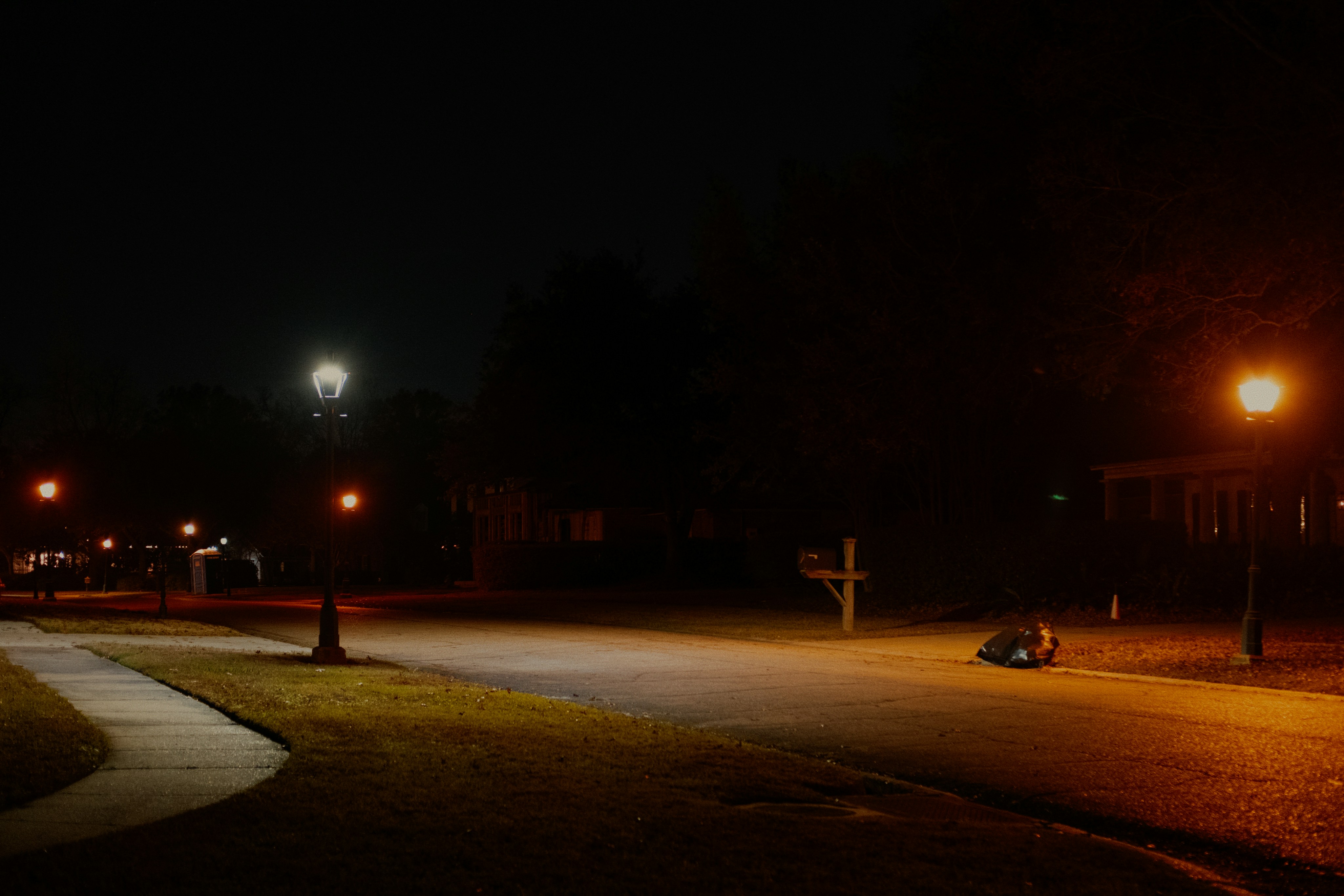 Streetlights illuminate a dark suburban street at night.