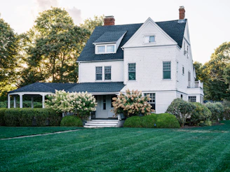 A large white house with a green lawn.